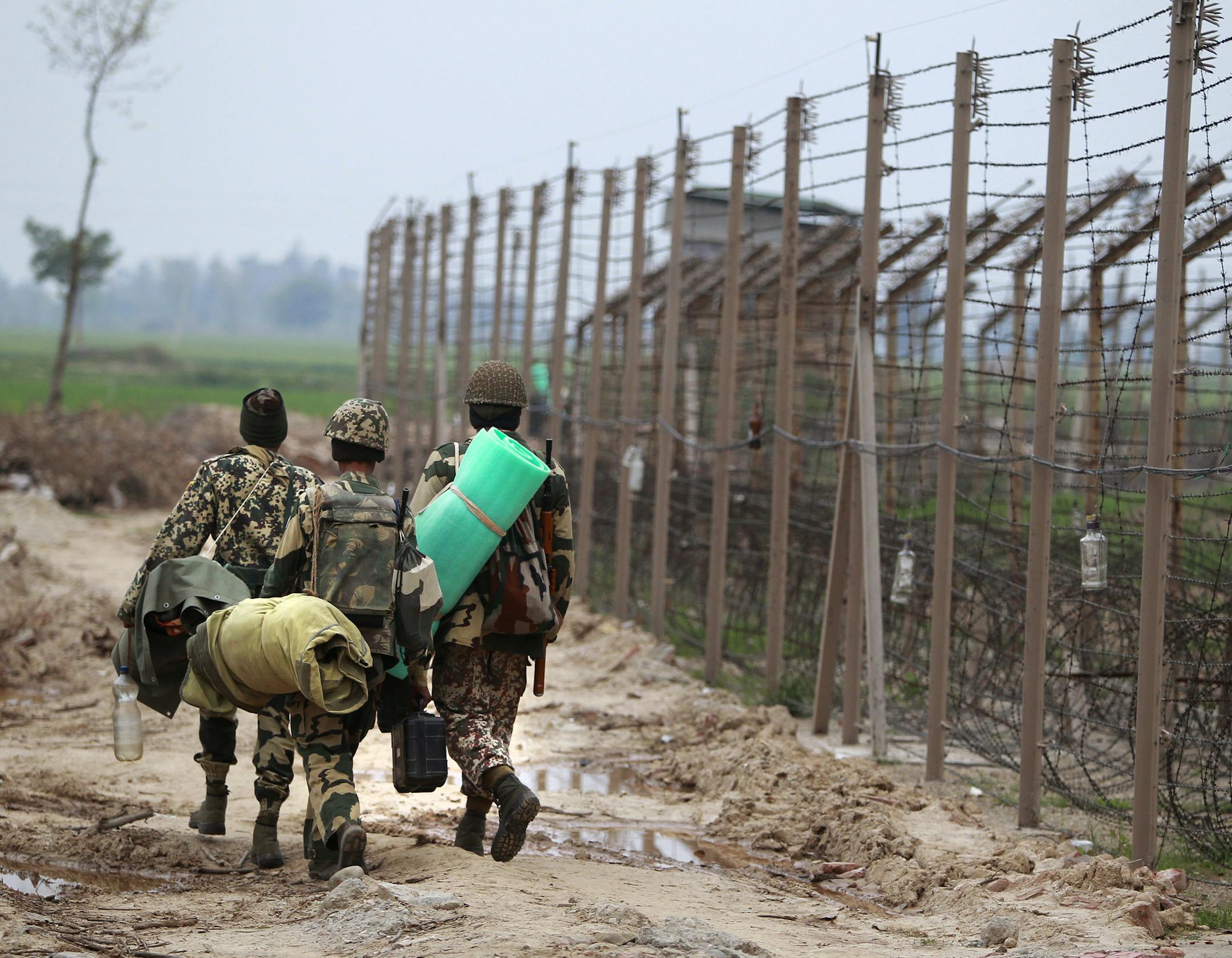 File - In this Wednesday, March 15, 2017, file photo, Indian Border Security Force soldiers, with their belongings, leave for their bunker at the India-Pakistan international border area at Suchetgarh in Ranbir Singh Pura, about 27 kilometers (17 miles) south of Jammu, India. India needed just two years to build a 550-kilometer (340-mile) fence along the disputed border area with Pakistan a decade ago. Now a high-tech barrier, it is laced with thermal imaging devices, motion sensors and lighting