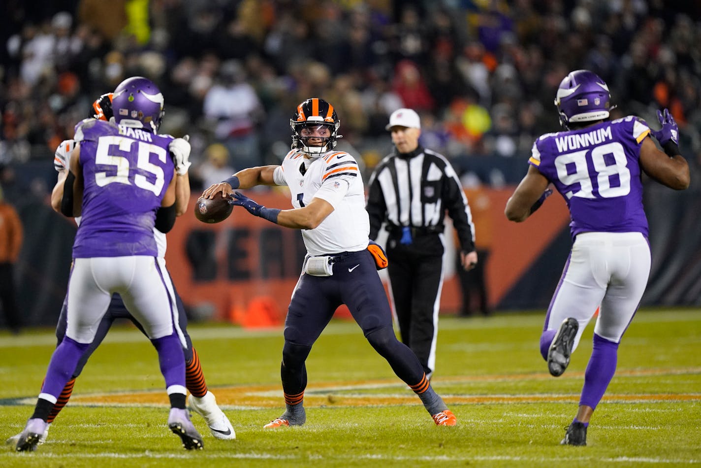 Chicago Bears quarterback Justin Fields (1) passes between Minnesota Vikings outside linebacker Anthony Barr (55) and defensive end D.J. Wonnum during the first half of an NFL football game Monday, Dec. 20, 2021, in Chicago. (AP Photo/Nam Y. Huh)