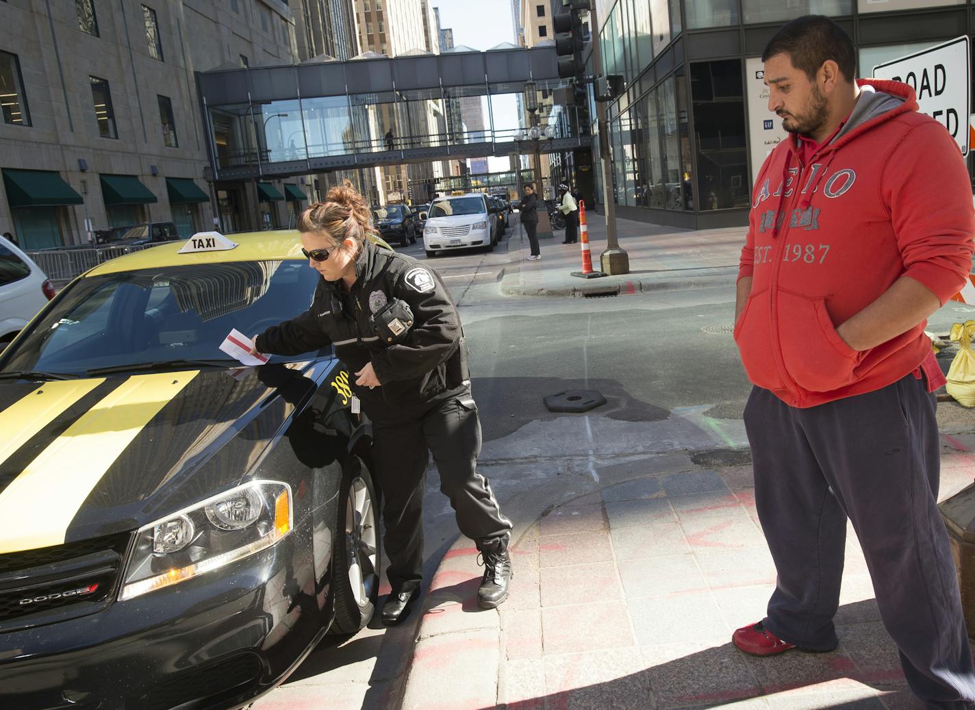 Cab driver Walter Mendez, right, was ticketed by a Minneapolis Traffic Control agent for obstructing traffic at 7th Street and Nicollet Tuesday afternoon. ] Aaron Lavinsky &#x2022; aaron.lavinsky@startribune.com Dozens of cabs clogged traffic along 7th street in downtown Minneapolis in what police are calling civil disobedience on Tuesday, Oct. 13, 2015. Drivers are upset with downtown hotels and believe they are cutting deals with limo drivers for clients and are cutting out taxi drivers' busin