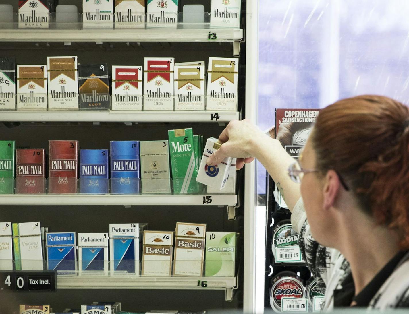 Michelle Kennedy grabbed a pack of cigarettes behind the counter for a customer at Vernon BP gas station in Edina, which along with St. Louis Park and Bloomington have raised the tobacco sales age from 18 to 21.