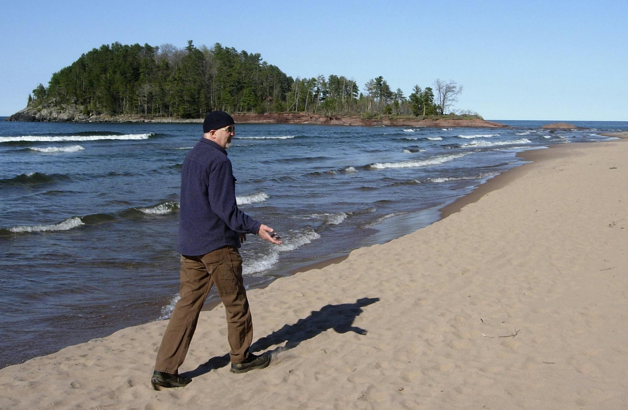 Marquette writer, James McCommon strides down the beach toward Little Presque Isle.