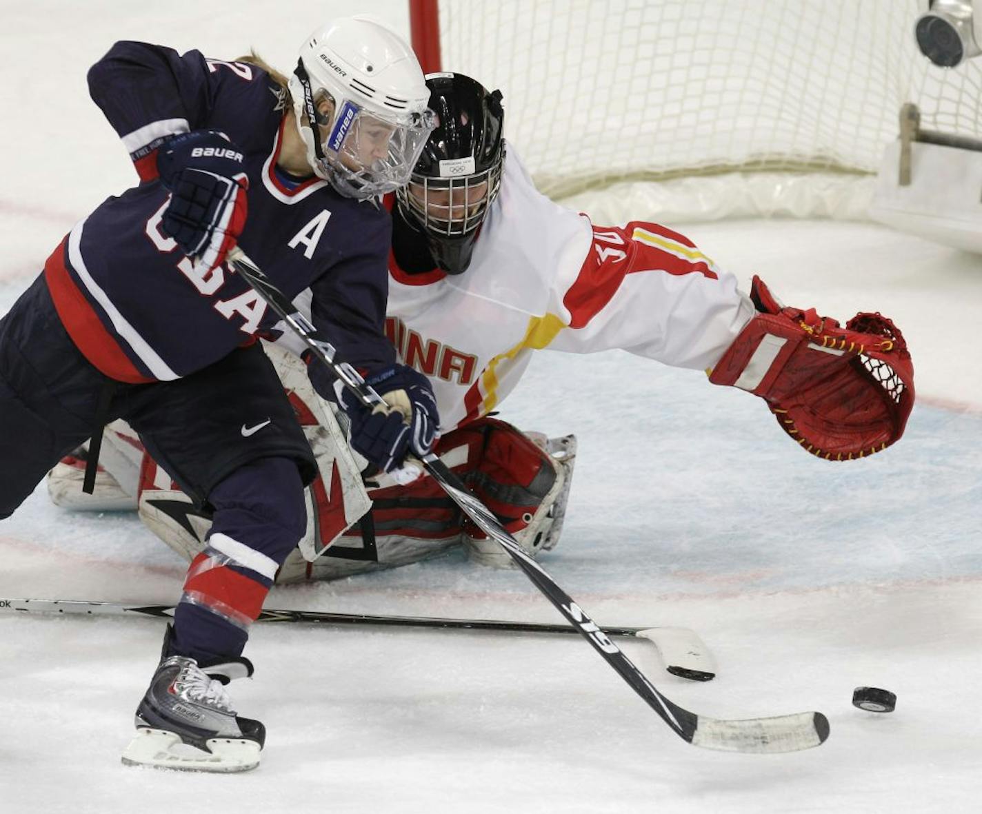 USA's forward Jenny Potter (12) scores past China's goal keeper Shi Yao (30) in the first period in women's preliminary round hockey play at the Vancouver 2010 Olympics in Vancouver, British Columbia, Sunday, Feb. 14, 2010.