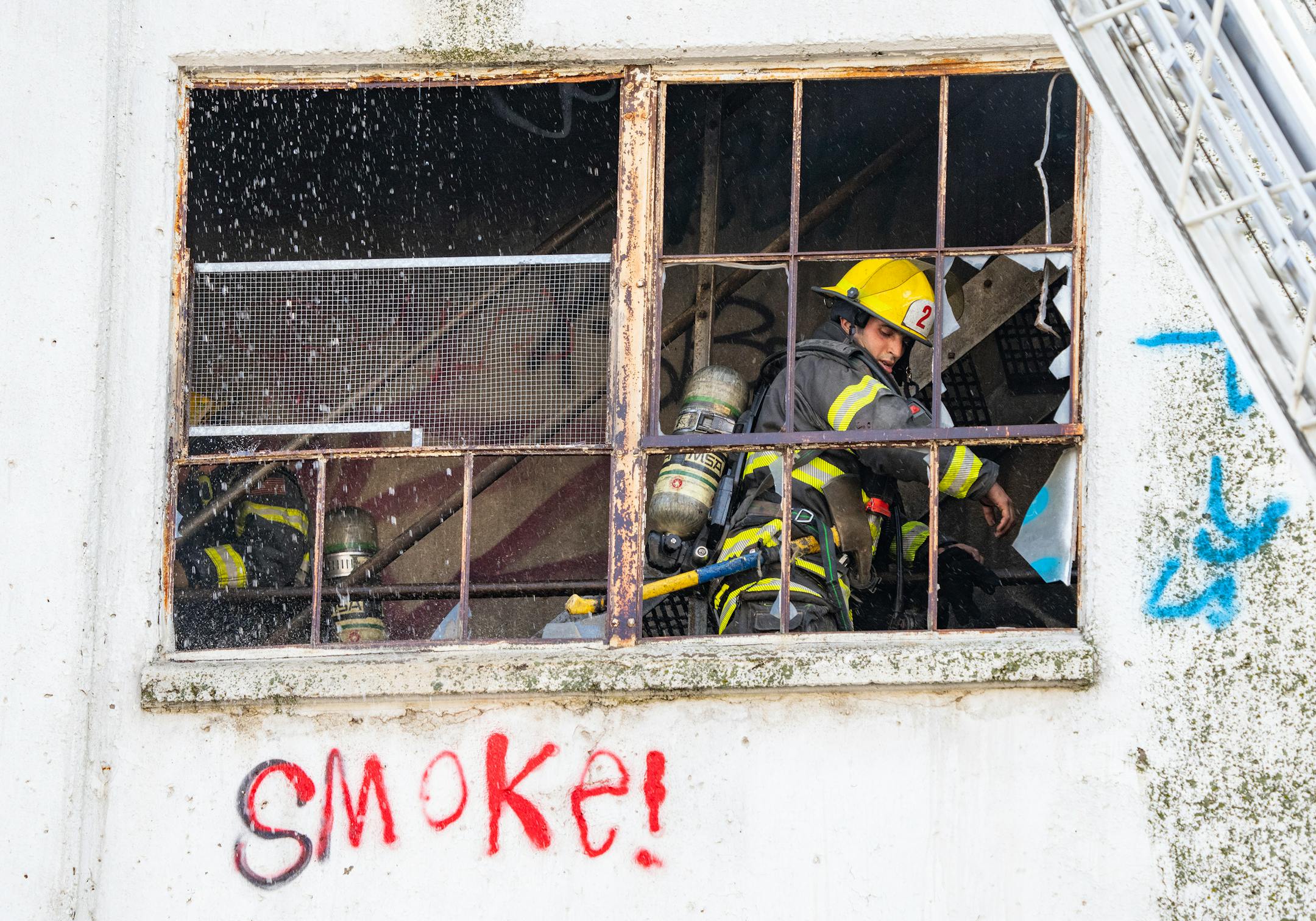 Firefighters, seen through windows, worked to put out a fire Wednesday in a grain elevator in south Minneapolis. Red graffiti on the building says "Smoke!"
