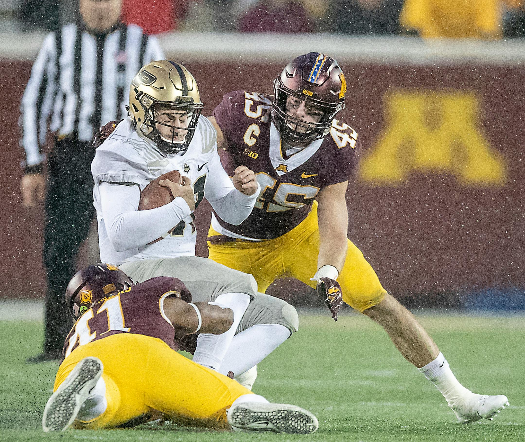 Gophers linebackers Carter Coughlin (45) and Thomas Barber brought down Purdue quarterback David Bloug.