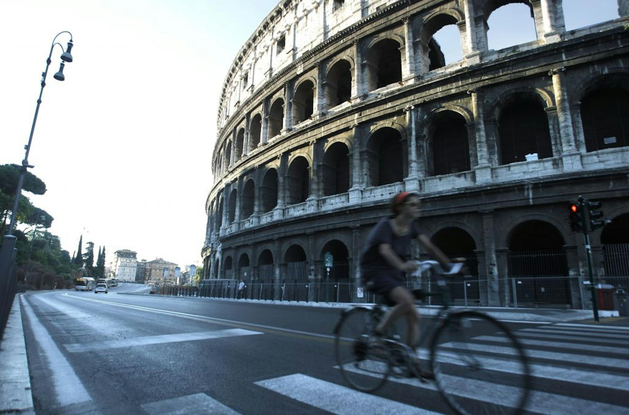 A man pedals along the Fori Imperiali avenue, with the Colosseum in background, Saturday, Aug. 3, 2013. Rome has begun a traffic ban to protect ancient glories from modern perils, allowing only buses, taxis, bicycles and pedestrians to go down the boulevard that runs between the Roman forums and curves around the Colosseum. Traffic police started enforcing the ban at dawn Saturday, diverting private cars and motor scooters to side streets, so they will no longer clog Via dei For Imperiali, a roa