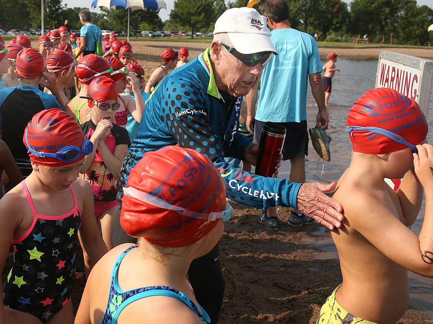 Triathlete Bob Powers, 91, encouraged athletes as they prepared to enter the water for the start of the race Saturday in Lake Elmo.