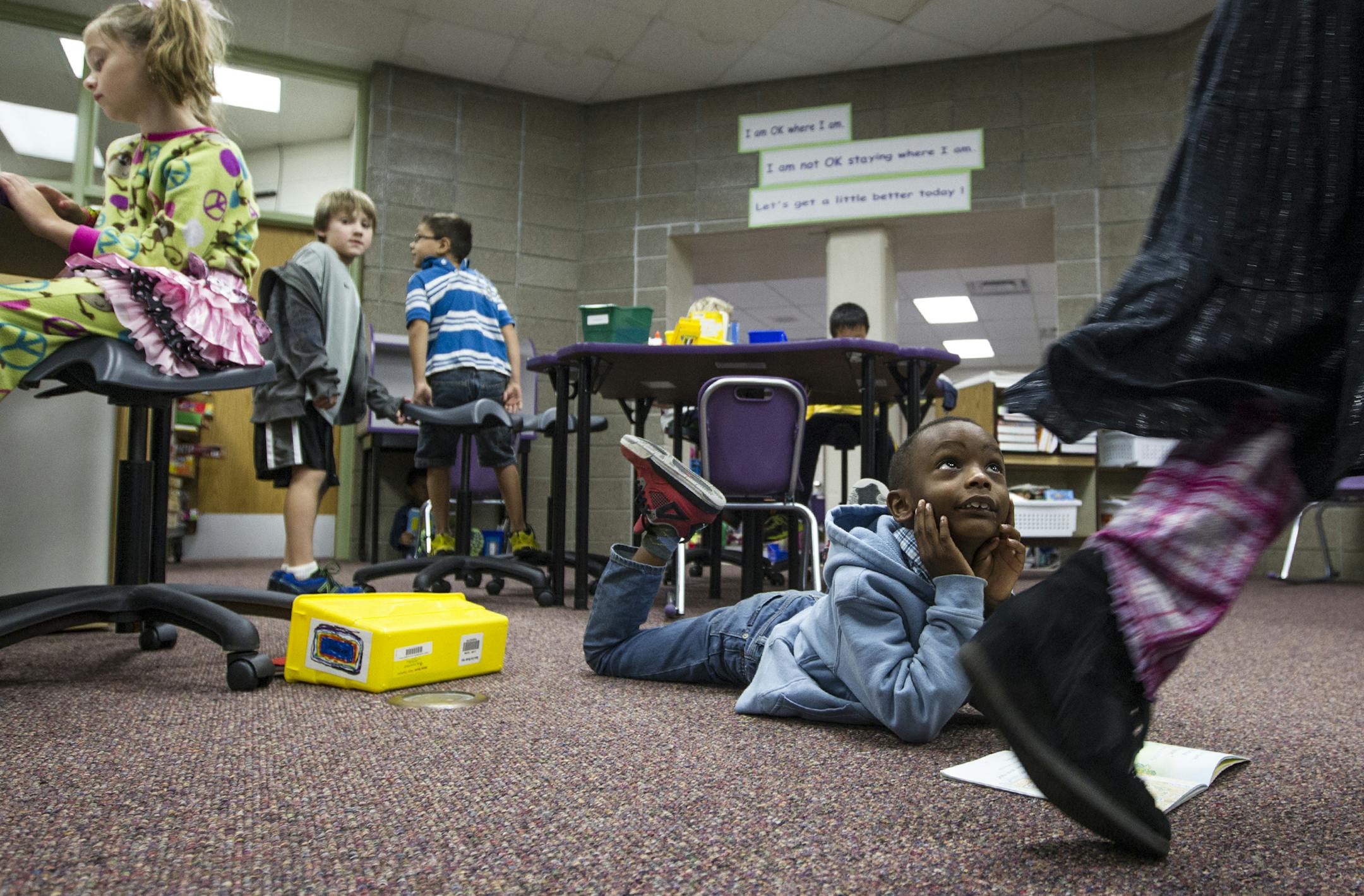 First grade student Remmy Njoroge, 6, glances up at a passing friend as students find individual areas to read and work at Impact Academy, a separate school program within Orchard Lake Elementary School in Lakeville October 8, 2013.