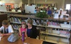 Amy DeYoung, of Ham Lake, reads with her daughters Arielle and Lillia on a recent afternoon in Centennial Library.