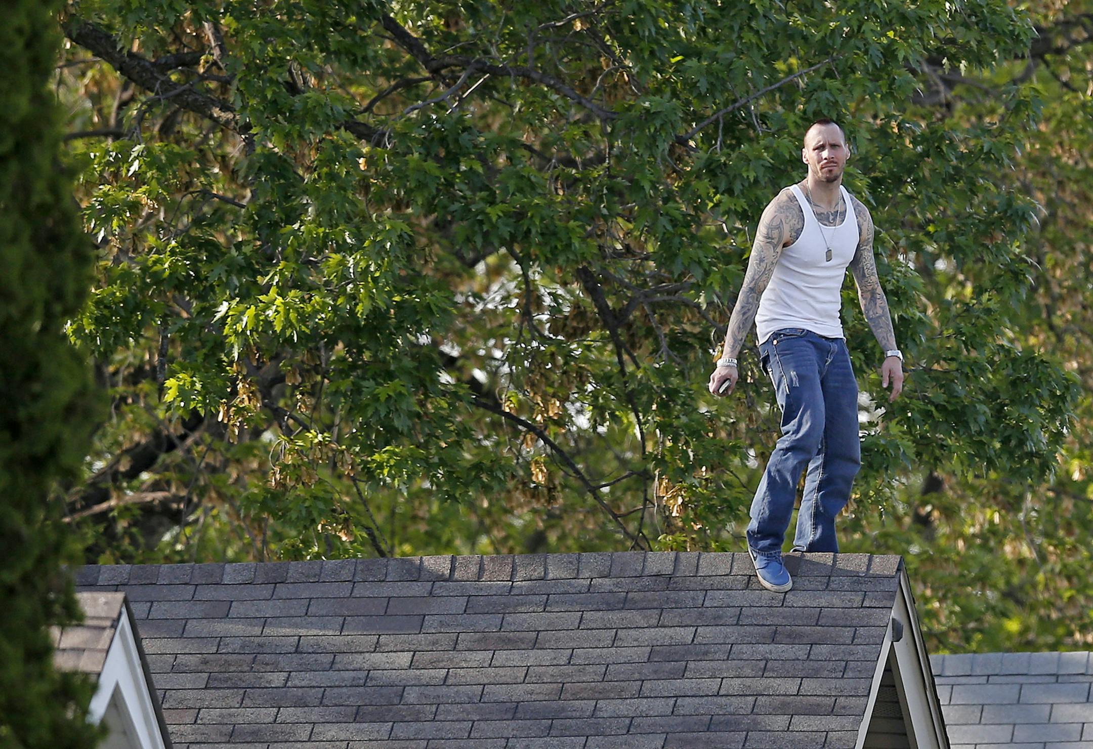 A suspect on the roof of a home on Freemont Ave. North in Minneapolis on Wednesday evening. ] CARLOS GONZALEZ cgonzalez@startribune.com, May 20, 2015, Minneapolis, MN, Police standoff at Freemont and 40th ORG XMIT: MIN1505201951201384