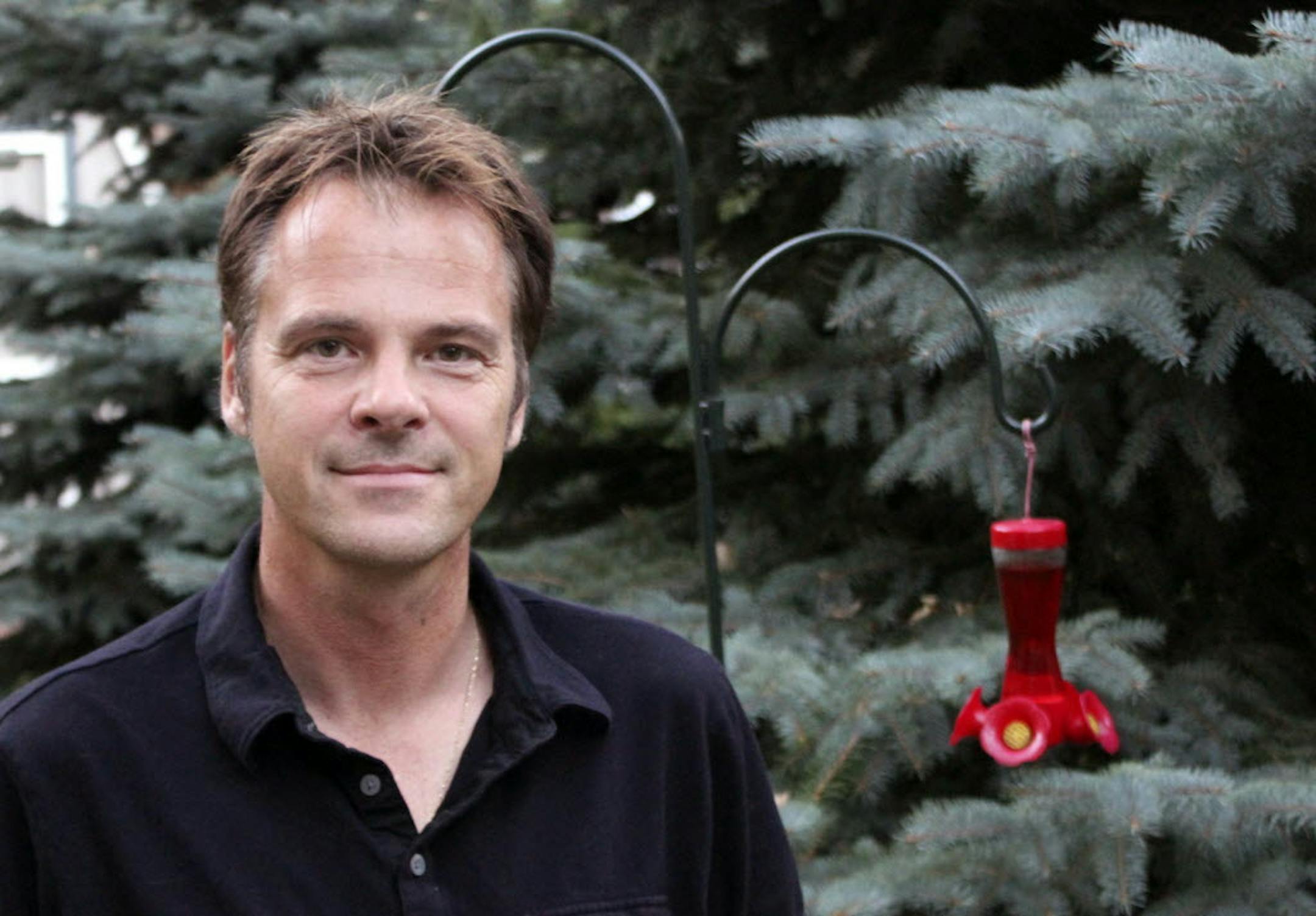 Wilderness canoeist Scott Pirsig poses for a photo next to a blue spruce and a hummingbird feeder in the back yard of his home on Tamra Lane in Albert Lea, Minn.