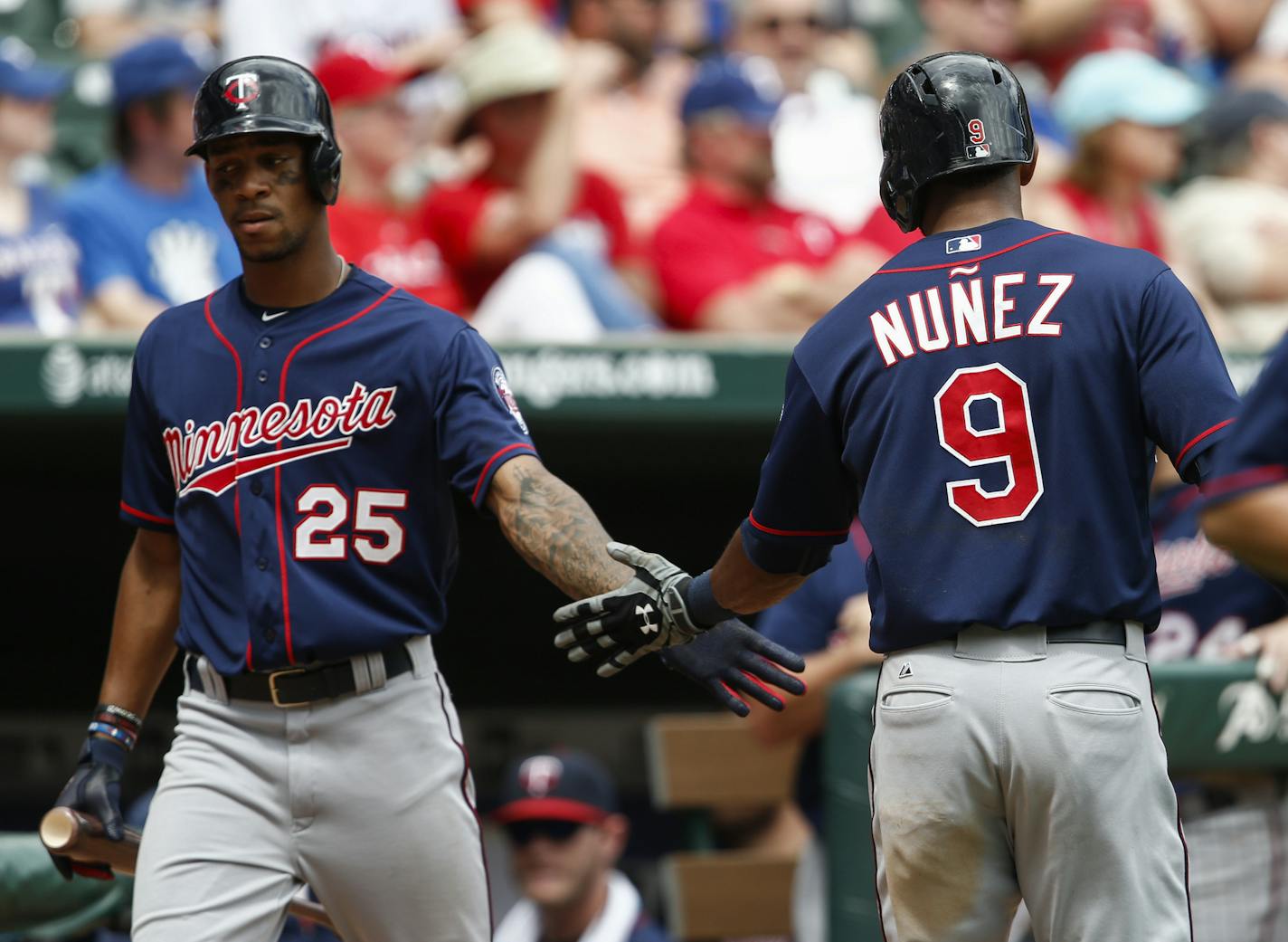 Minnesota Twins' Eduardo Nunez (9) is congratulated by Byron Buxton (25) after scoring on a triple by Shane Robinson against the Texas Rangers during the sixth inning of a baseball game, Sunday, June 14, 2015, in Arlington, Texas. (AP Photo/Jim Cowsert)