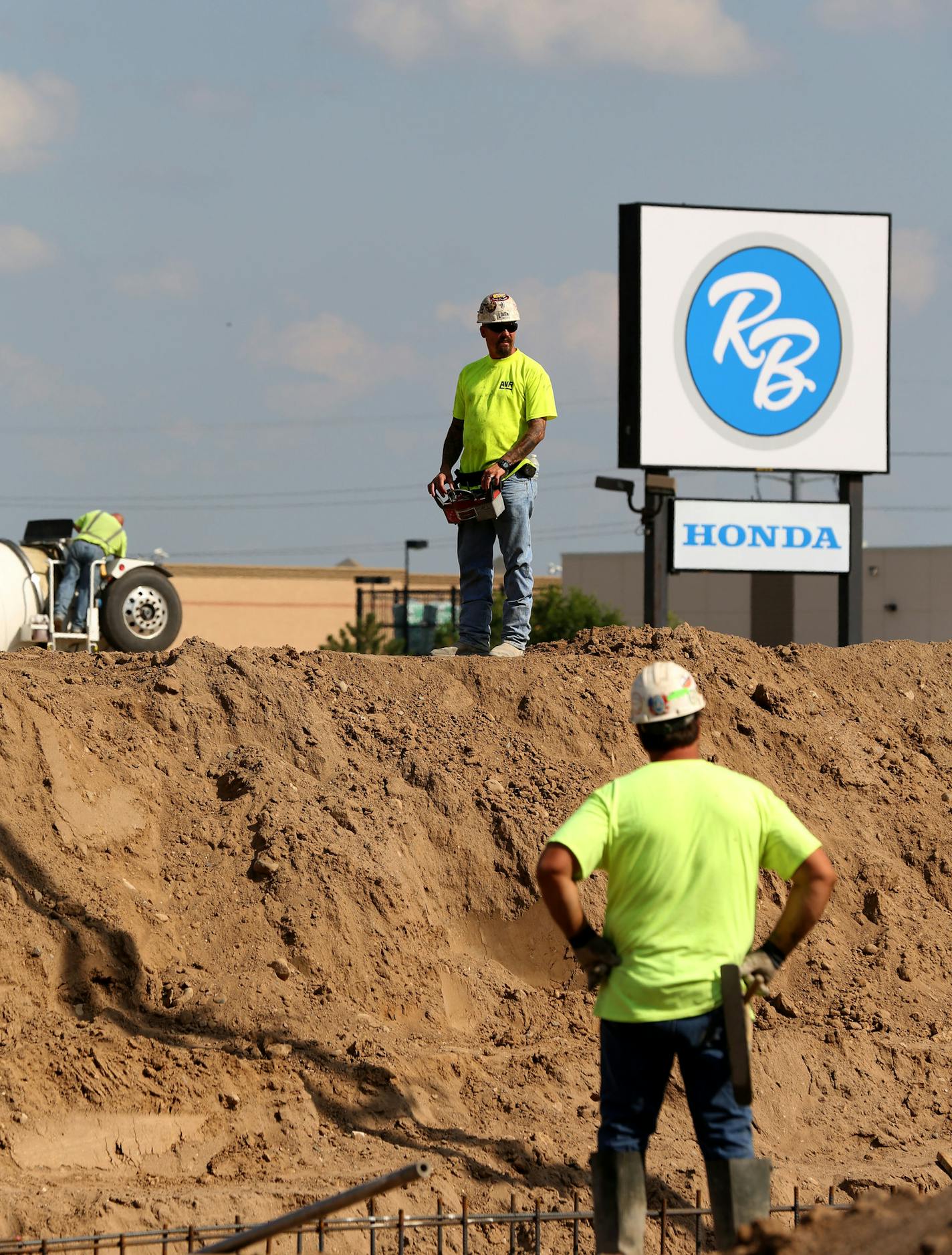 Workers kept watch as others pour the cement for the footings for the expansion of the Richfield Bloomington Mitsubishi and Honda dealership. ] (KYNDELL HARKNESS/STAR TRIBUNE) kyndell.harkness@startribune.com At the Richfield Bloomington Mitsubishi and Honda dealership in Richfield Min. Wednesday, August, 13, 2014.