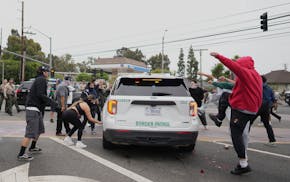 Protesters kick the side of a Border Patrol vehicle during a demonstration over the dozens detained in an operation by federal immigration authorities
