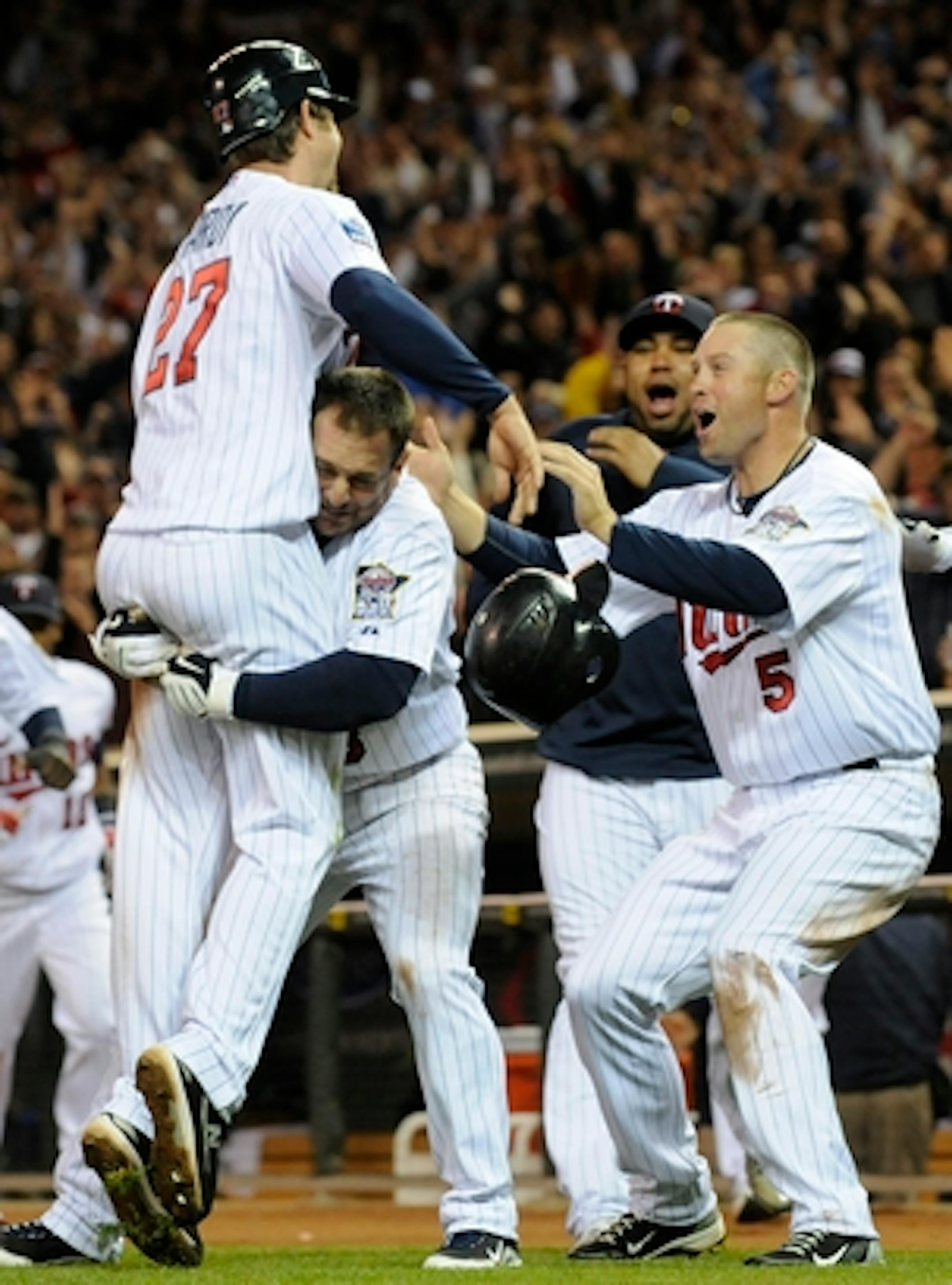 Minnesota Twins' Nick Punto loses his helmet as he hoists J.J. Hardy, left, after Hardy scored the winning run on a wild pitch by Detroit Tigers' Ryan Perry in the ninth inning of a baseball game Tuesday, May 4, 2010 in Minneapolis. The Twins won 4-3. At right is Michael Cuddyer. (AP Photo/Jim Mone)