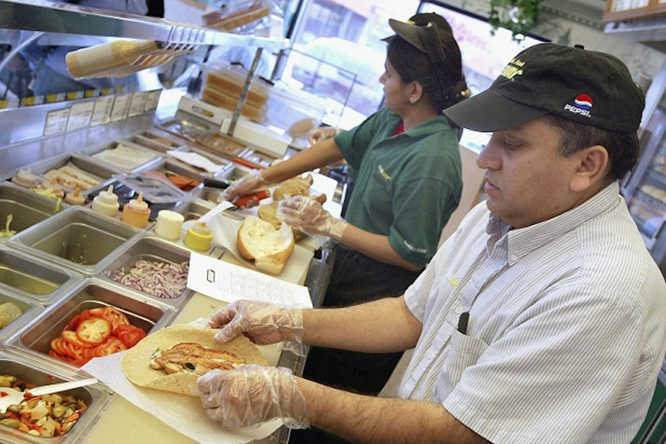 Workers prepare chicken sandwiches at a Subway store.