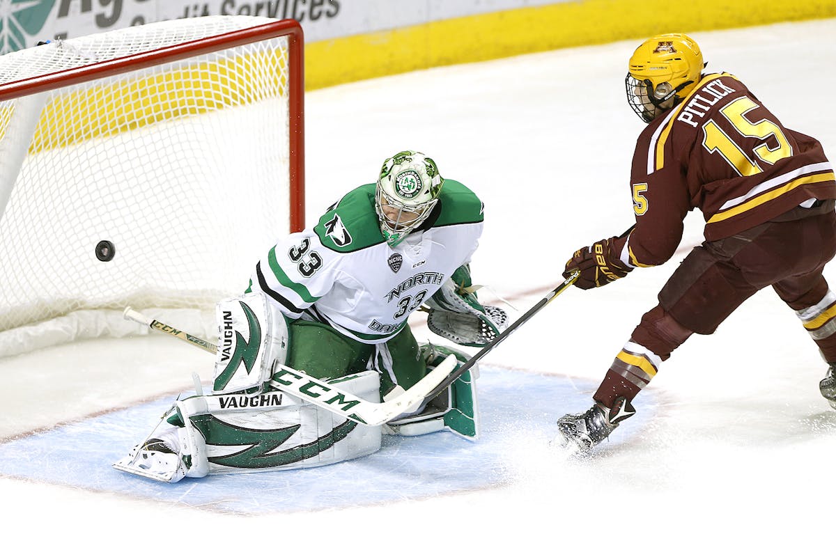 Minnesota's Rem Pitlick scores on UND goalie Cam Johnson in the first period. photo by Eric HYlden/Grand FOrks Herald