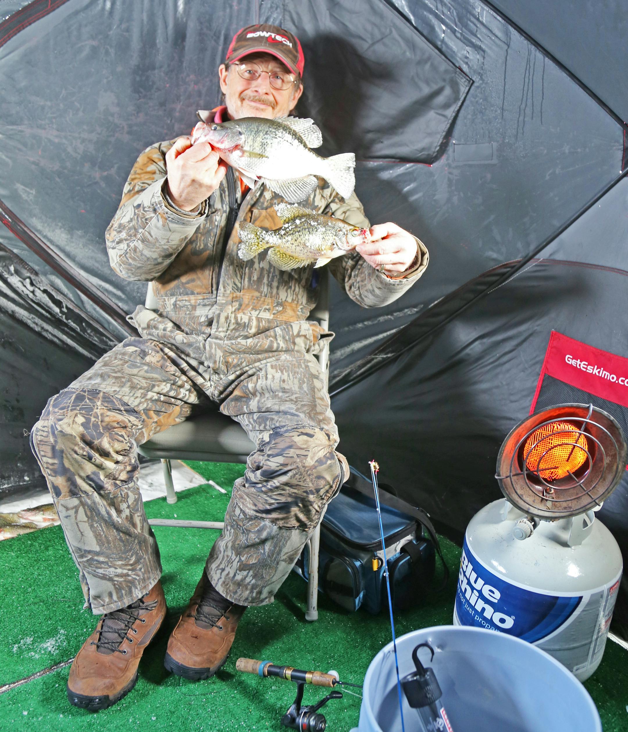 Larry Schlais of Minneapolis shows off a couple of crappies he caught while fishing in his heated portable shelter on the St. Croix River last week. Fishing "is slow but it's fun'' on the river, he said.