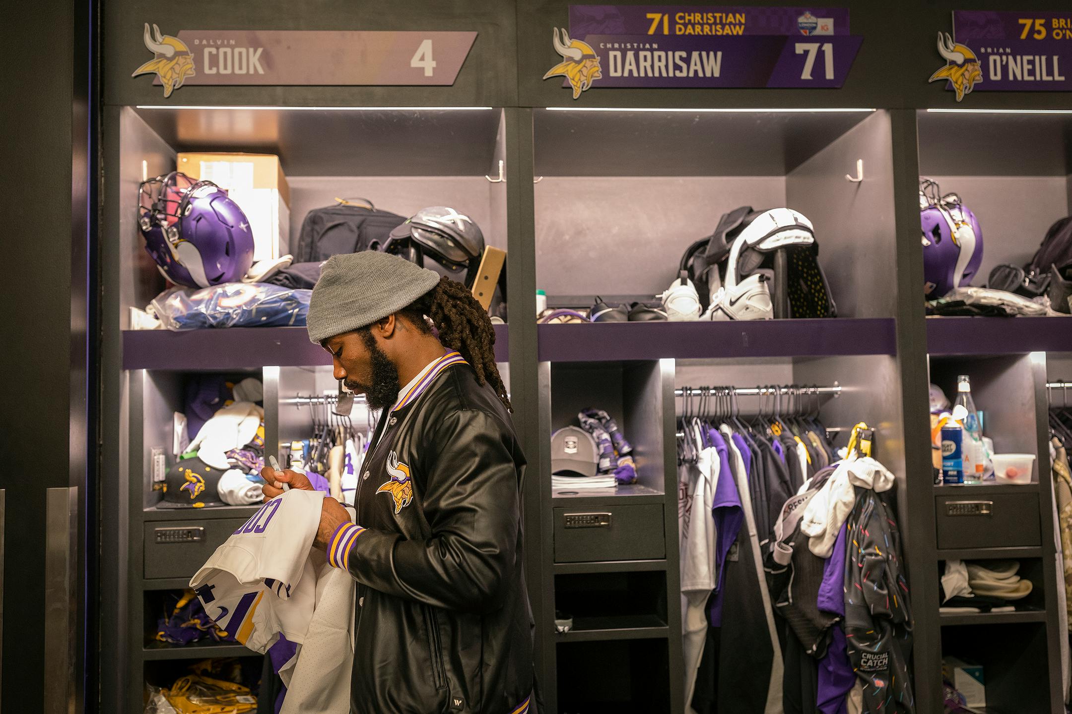 Minnesota Vikings running back Dalvin Cook (4) signs a jersey by his locker at the TCO Performance Center.
