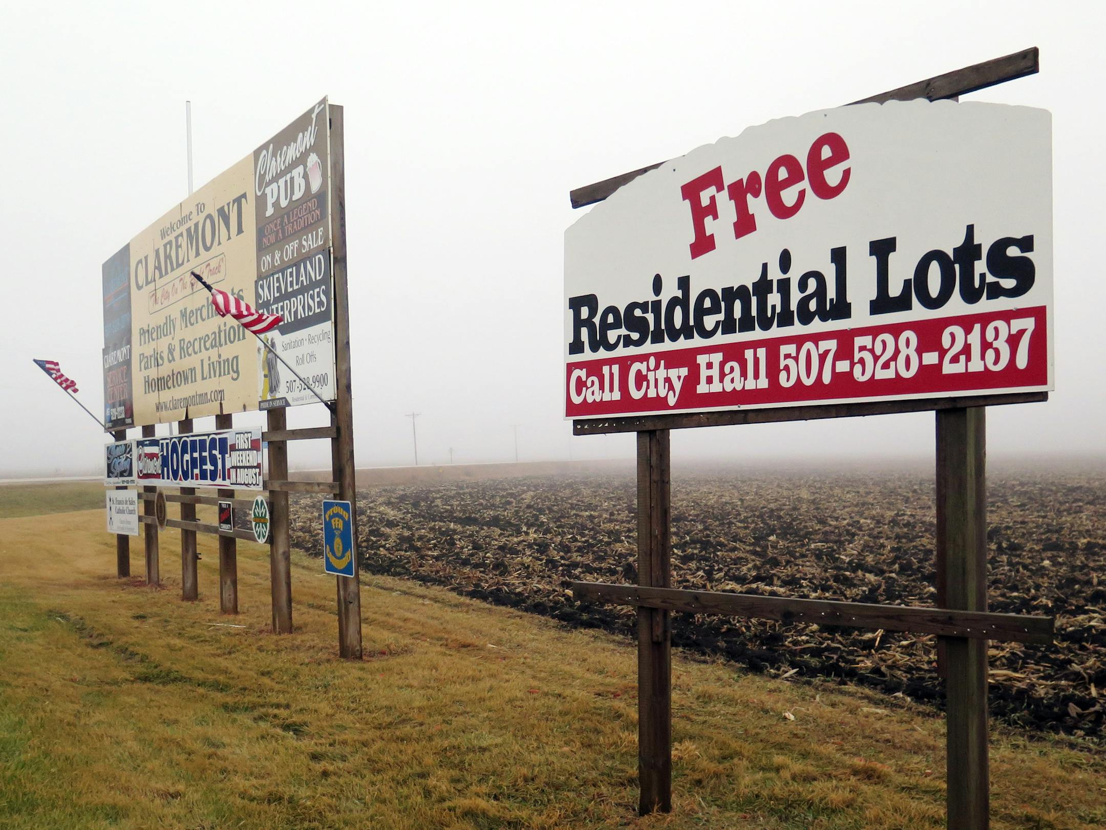 In this Dec. 14, 2014 photo, signs advertising free residential lots are seen in Claremont, Minn. A small southeastern Minnesota community is trying but failing to give away land for free. Claremont, which has about 500 residents, has had no takers in the three years it has been offering free lots to anyone with a qualifying income who is willing to build a house, Minnesota Public Radio News reported. (AP Photo/Minnesota Public Radio, Elizabeth Baier)