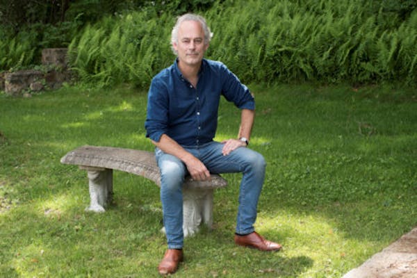 photo of author Amor Towles on a bench in a park