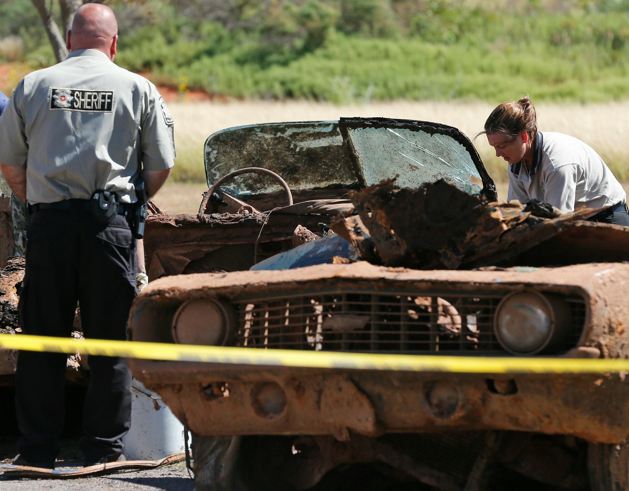 Officials work on the second of two cars found in Foss Lake in Foss, Okla., Wednesday, Sept. 18, 2013. The Oklahoma State Medical Examiner�s Office says authorities have recovered skeletal remains of multiple bodies in the Oklahoma lake where the cars were recovered.