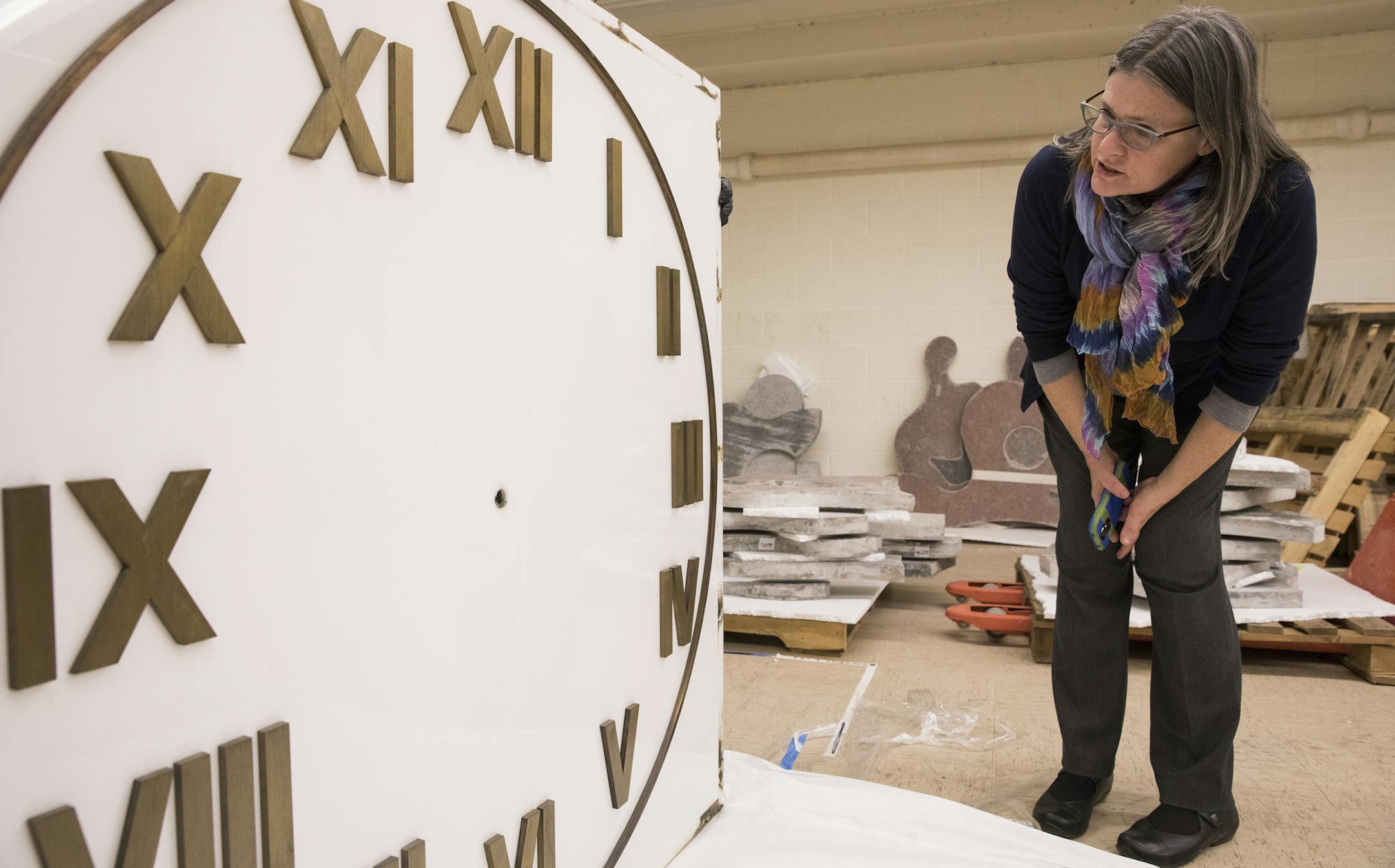 Mary Altman, a public arts administrator with the city of Minneapolis, takes a look at one of the faces of a sculpture clock in storage in the basement of the IDS Building.] (Leila Navidi/Star Tribune) leila.navidi@startribune.com BACKGROUND INFORMATION: Art preparators unpack the face of a clock in storage in the IDS Building in downtown Minneapolis on Monday, December 5, 2016. A clock that dazzled city residents with an array of moving sculptures when it debuted on the new Nicollet Mall in the