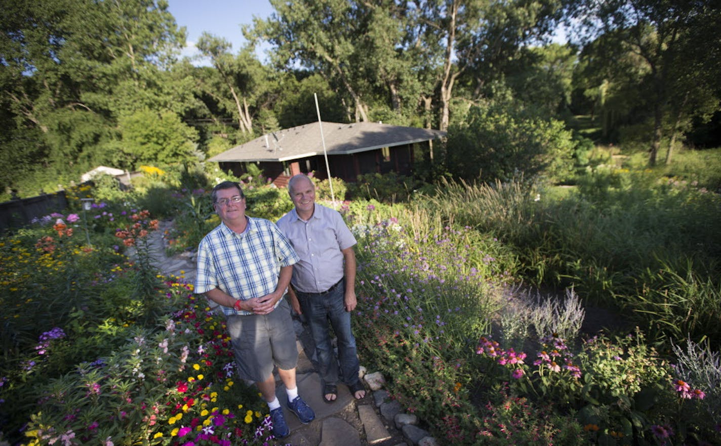 Reid Smith, left, and LaWayne Leno designed and tend their sprawling multitiered gardens, filled with vibrant annuals and perennials, in their Dellwood yard.