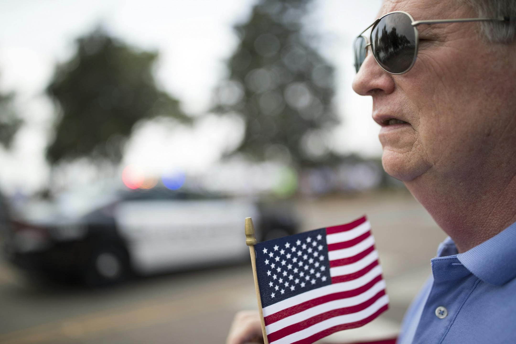 Lowell Lankford of Plymouth held and American Flag as the funeral processions for Wayzata Police Officer Bill Mathews passed by Lake Minnetonka to Summit Park Cemetery were he will be buried Thursday September 14,2017 in Wayzata, MN.
