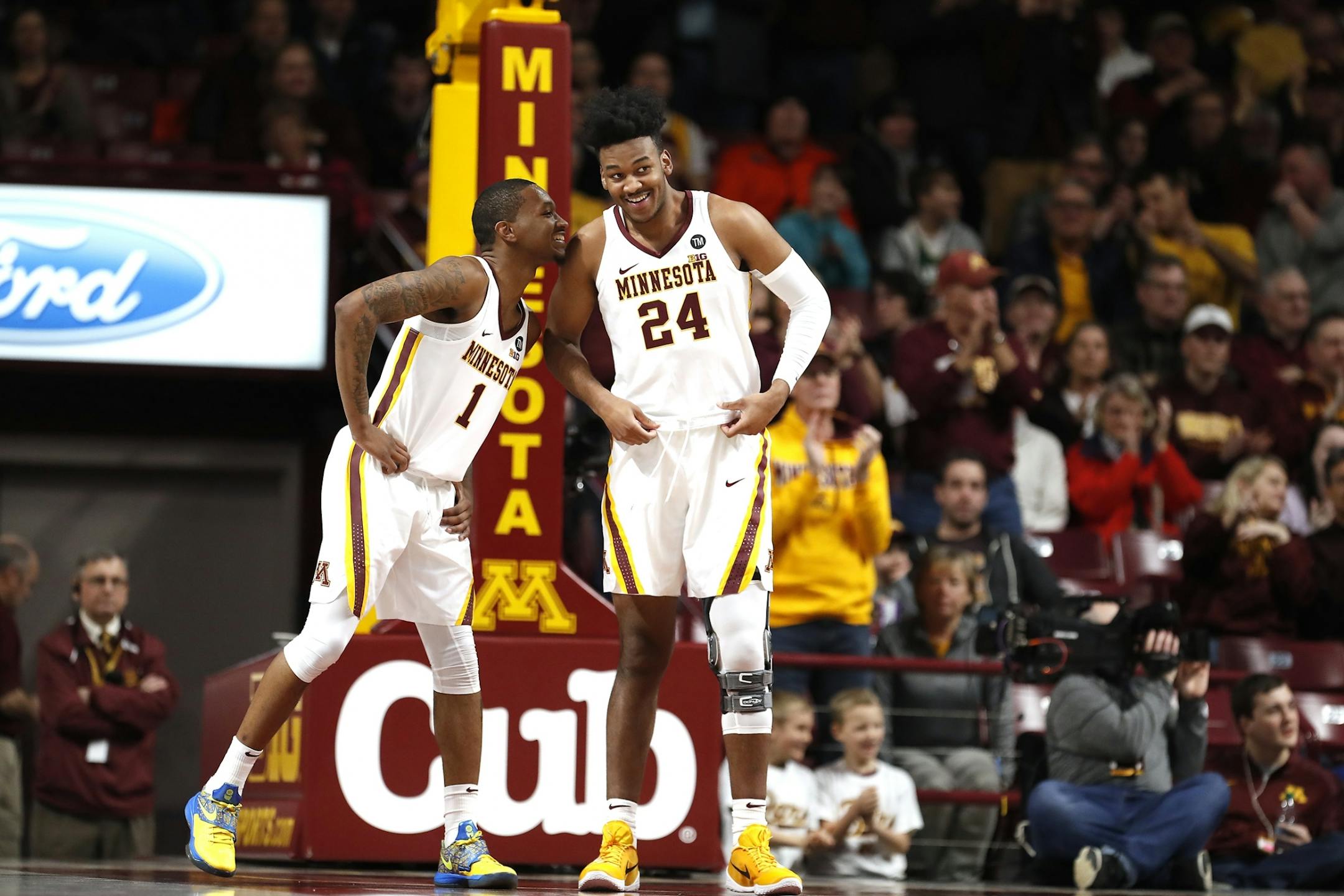 Minnesota forward Eric Curry (24) chats with Minnesota guard Dupree McBrayer (1) just after entering the game for the first time during the first half.
