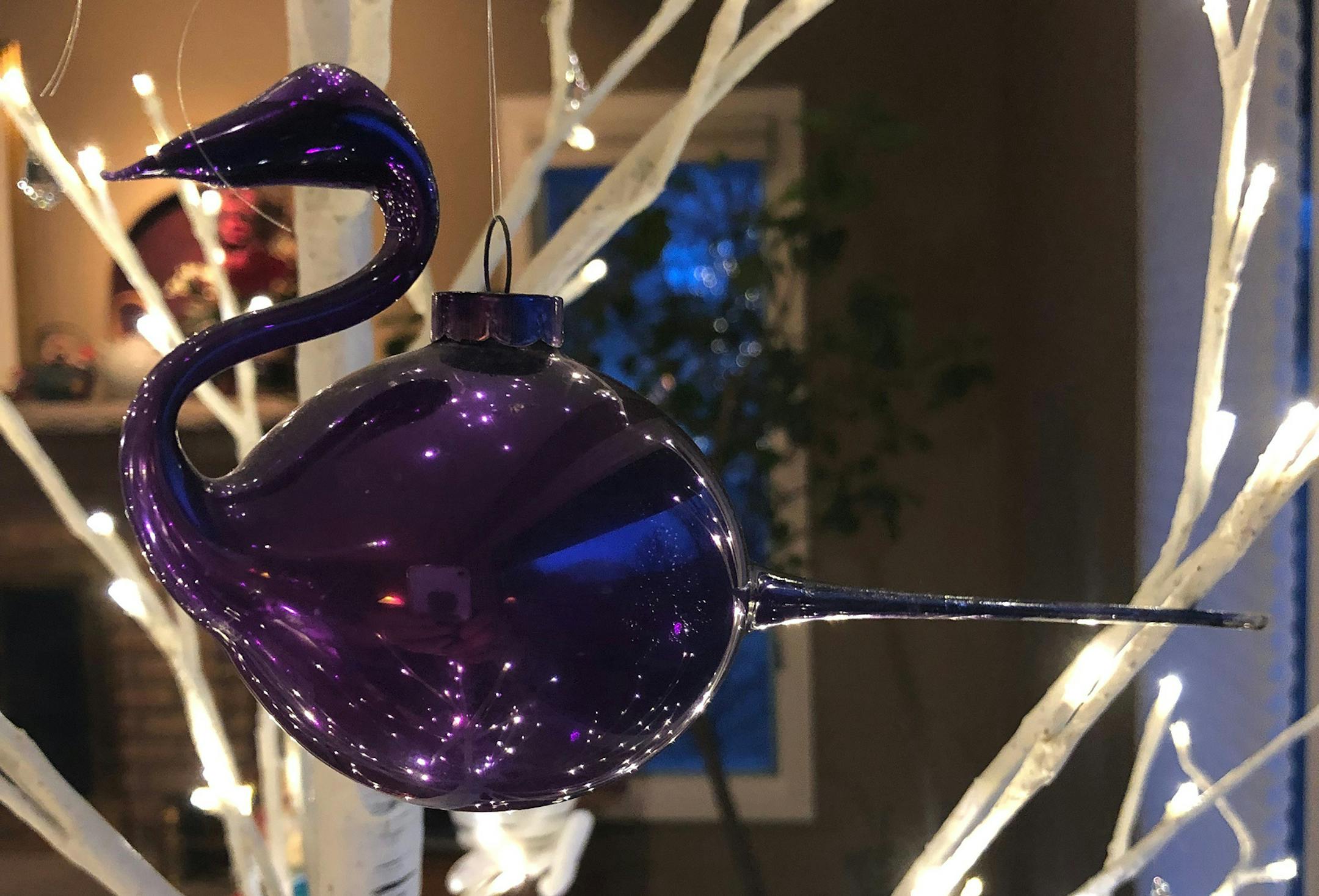 Marjorie Herdes
In 1949 my preschool class visited a glass blower. I was enchanted. He handed me the ornament that he blew as a demonstration for us - a purple swan. I brought it carefully home and it has been a treasured centerpiece of our family Christmas tree ever since, saved in the original candy box padded with now very old cotton . As you can imagine it has been handled with extreme love and care for low these 60 years- through toddlers and pets of all kinds. A gramma now most of my ornam