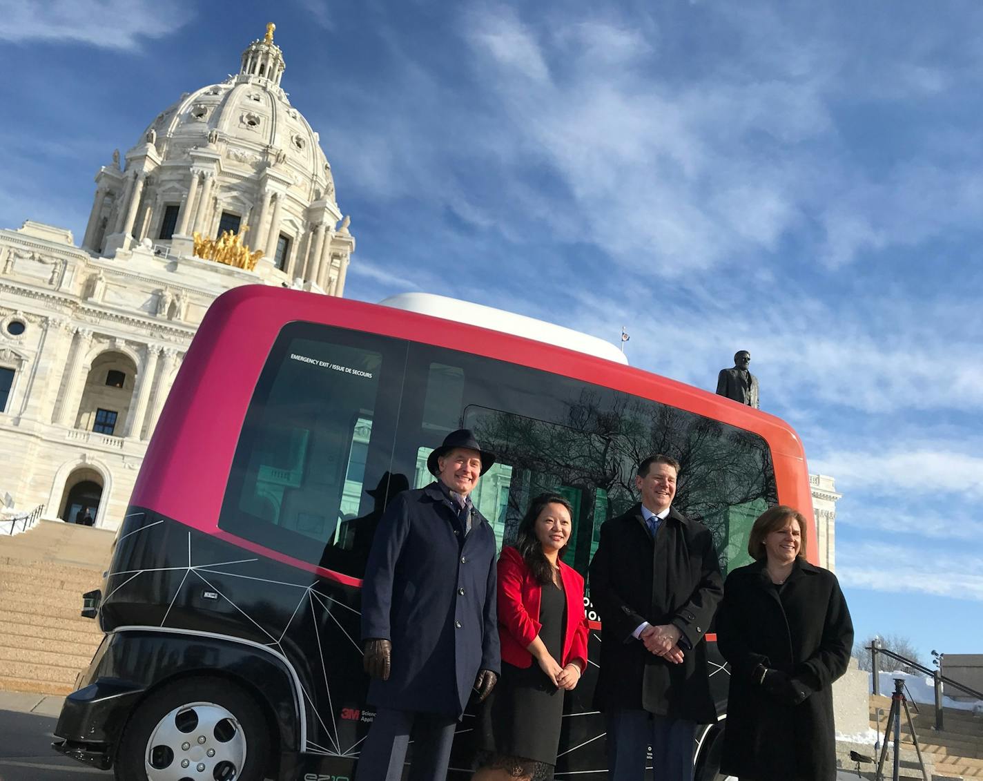 Transportion Commissioner Charlie Zelle, State Rail Director Tenzin Dolkar, Xcel Energy Minnesota President Christopher Clark, and Public Safety Commissioner Mona Dohman pose in front of MnDOT's autonomous shuttle at the Capitol on Wednesday.