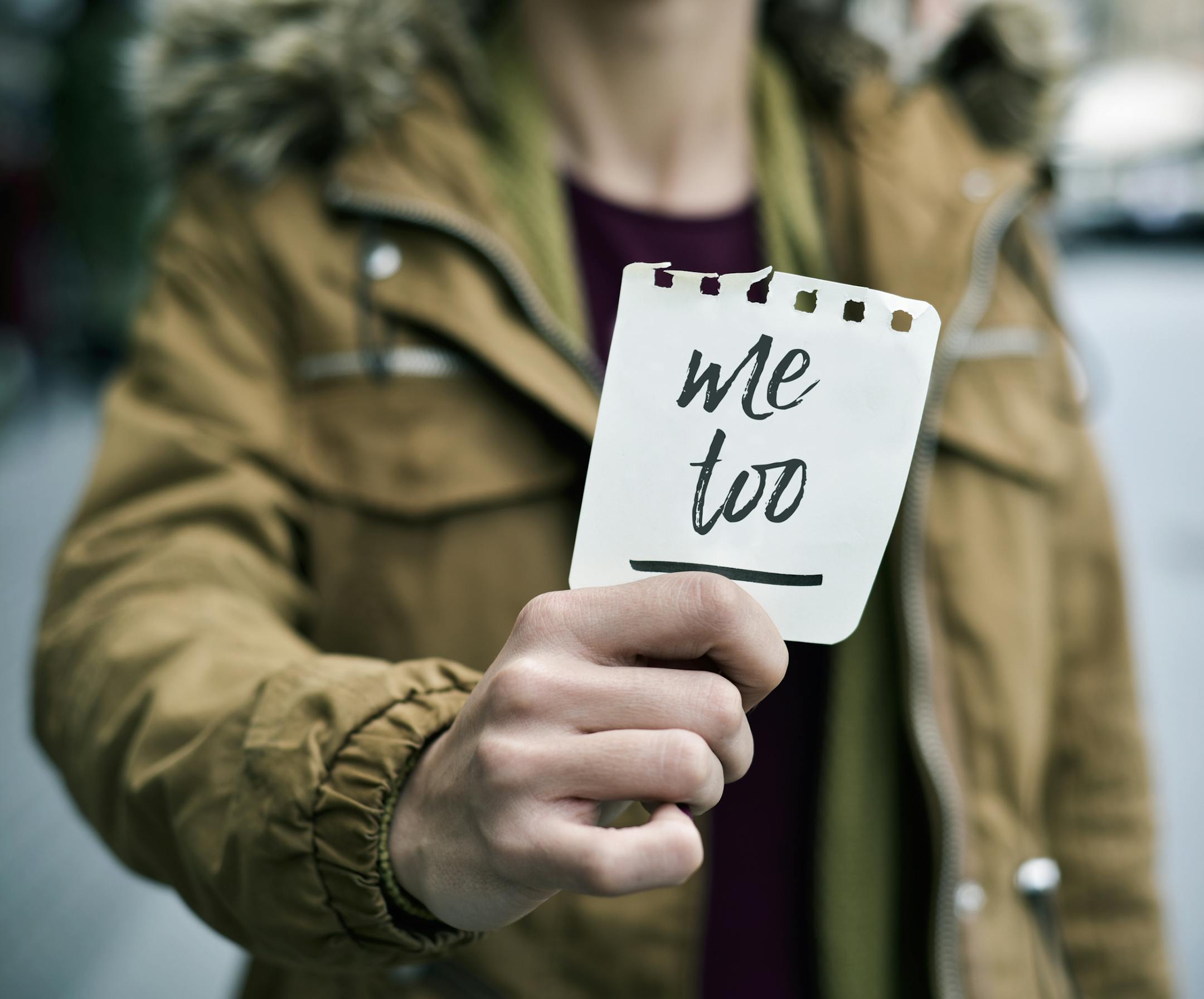 closeup of a young caucasian woman in the street showing a piece of paper with the text me too written in it. istock