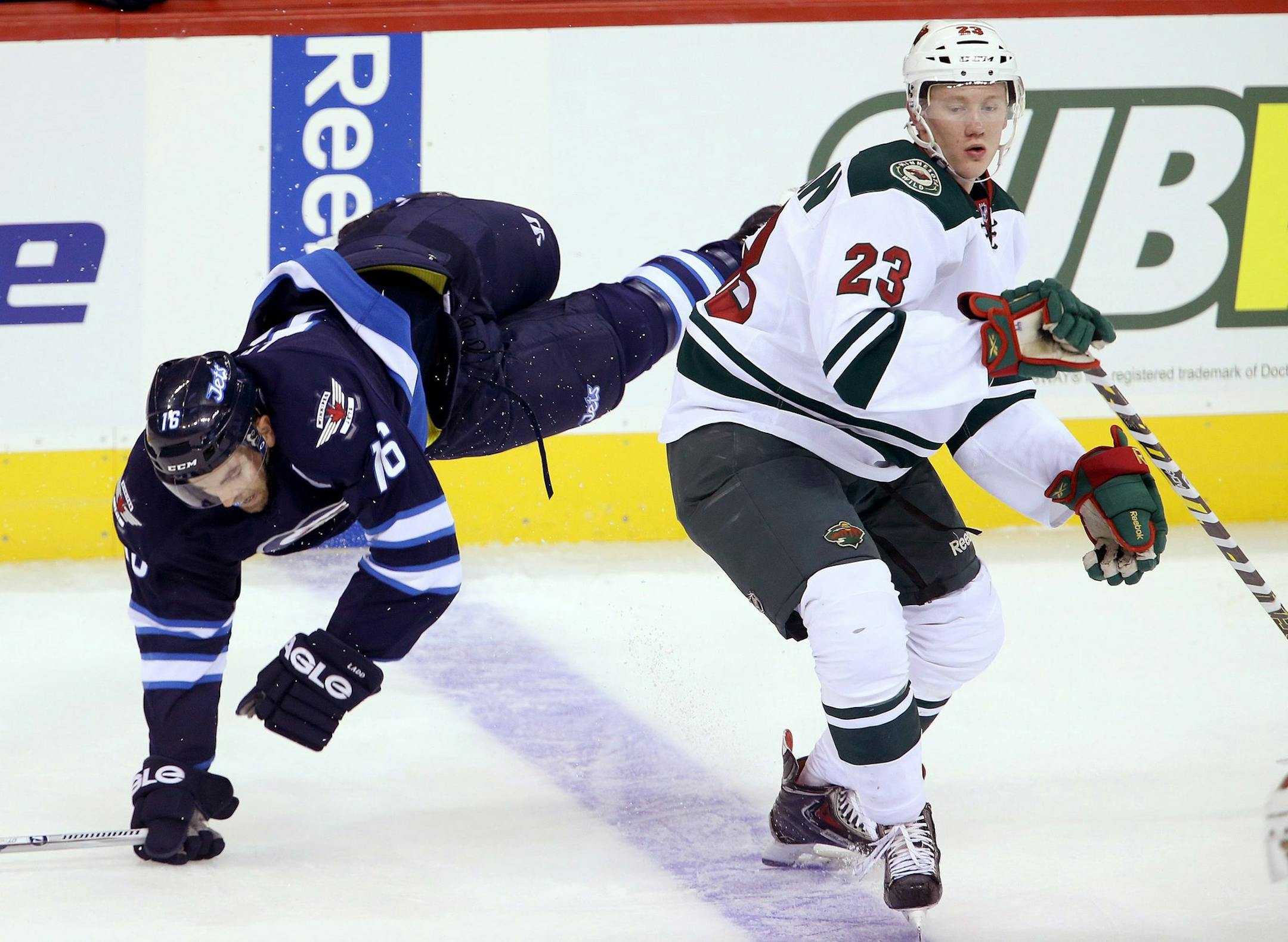 FILE - Winnipeg Jets' Andrew Ladd (16) goes over the back of Minnesota Wild's Gustav Olofsson (23) during first period pre-season NHL hockey action at MTS Centre in Winnipeg, Monday, Sept. 22, 2014. (AP Photo/The Canadian Press, Trevor Hagan)