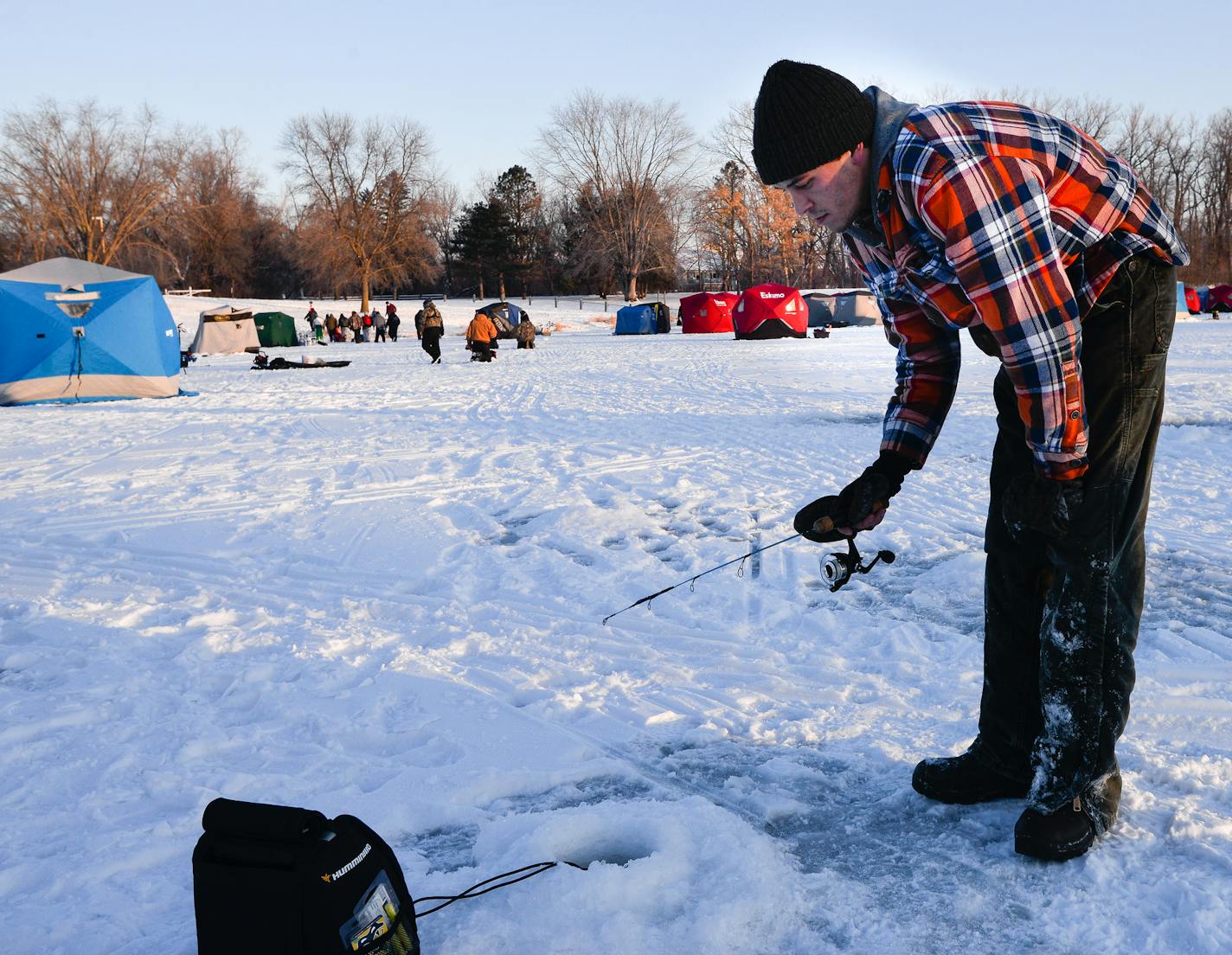 Chris Toll, 25, of Minneapolis, fishes from a hole outside of his ice house on Courthouse Lake in Chaska. Toll used cooked shrimp from a grocery store party platter as bait. ] (LIZ SAWYER/STAR TRIBUNE) liz.sawyer@startribune.com Anglers made the annual pilgrimage to Chaska's Courthouse Lake on Saturday, Jan. 14, 2017 for the winter trout season opener.