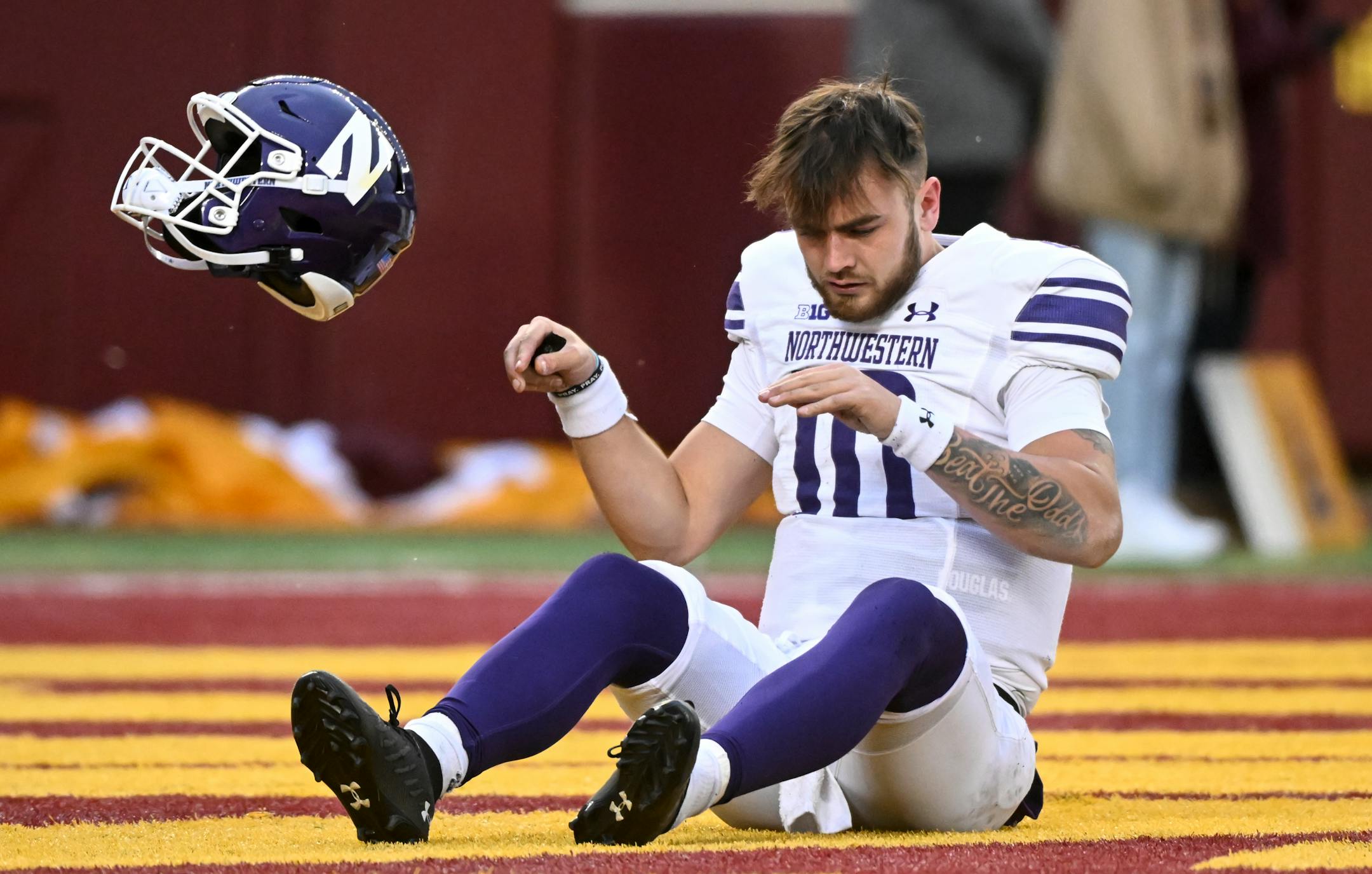 Northwestern Wildcats quarterback Brendan Sullivan (10) tosses off his helmet after he was tackled and injured during the first half.