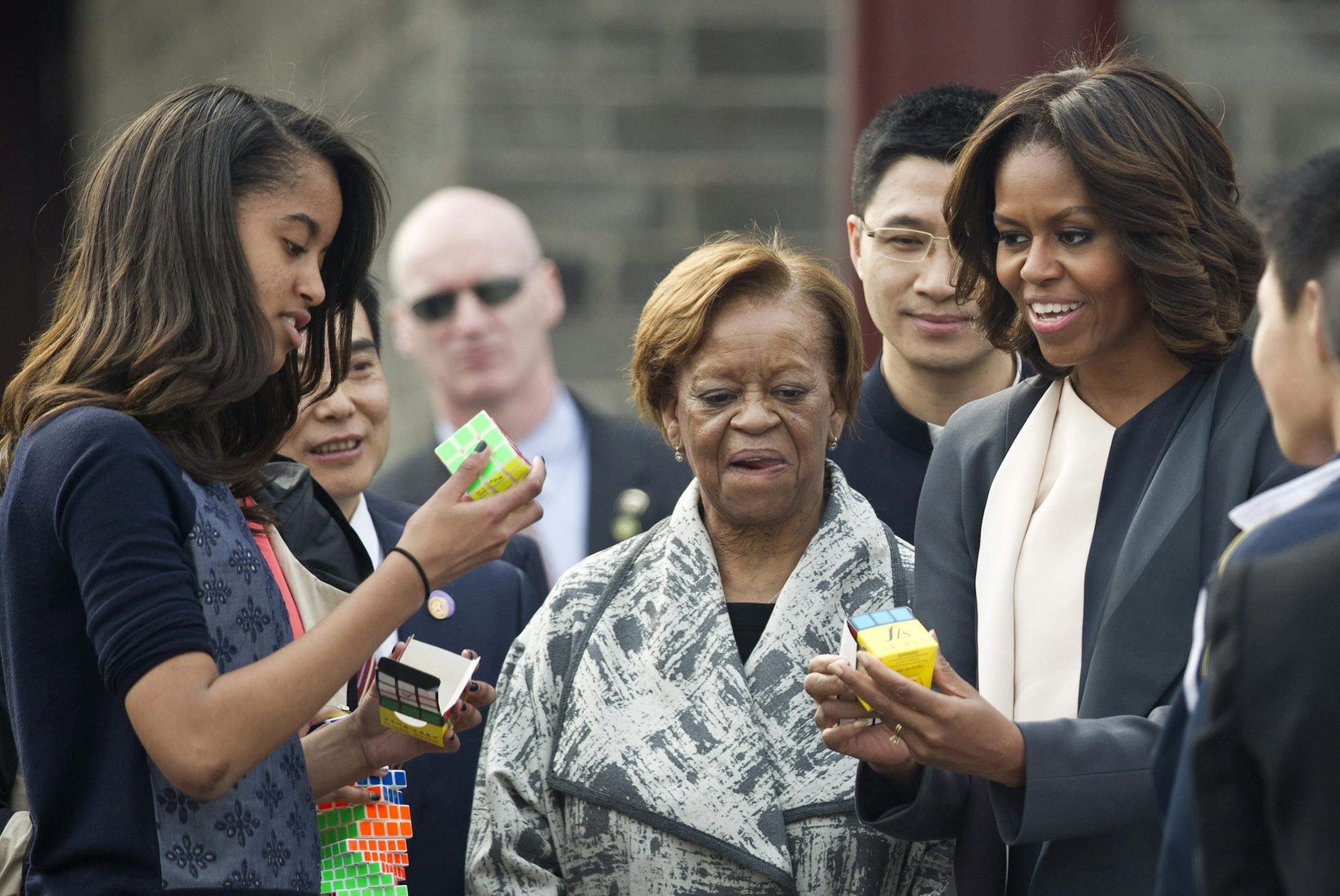 U.S. first lady Michelle Obama, right, plays a mini cube with her daughter Malia, left, during her visit to an ancient city wall with her daughters and her mother Marian Robinson, center, in Xi'an, in northwestern China's Shaanxi province, Monday, March 24, 2014. (AP Photo/Alexander F. Yuan)