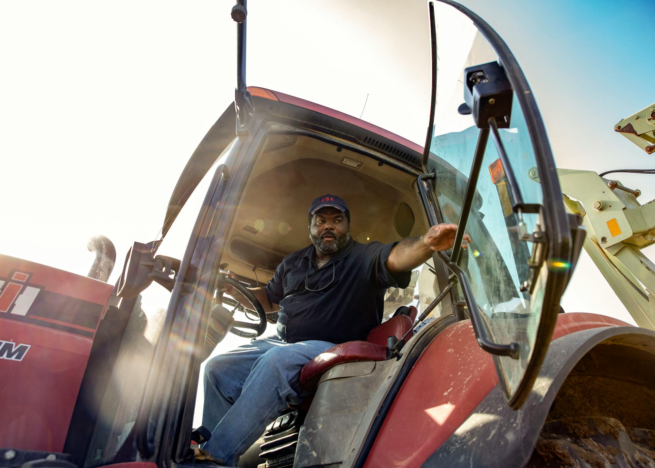 A farmer closes the door to his tractor.