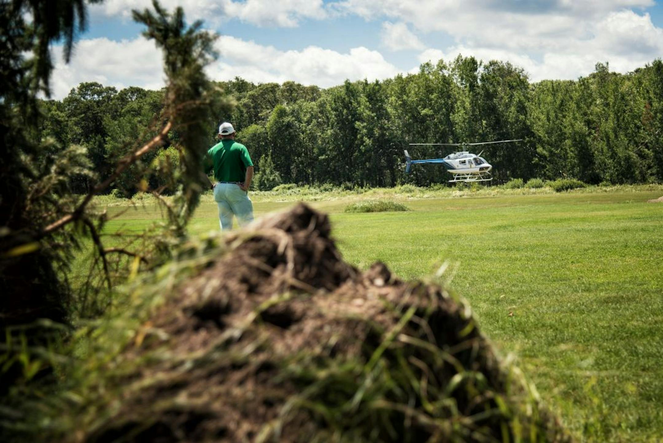 With a downed spruce tree in the foreground, Cragun's Resort golf pro Chris Foley watches as Gov. Mark Dayton and Rep. Rick Nolan, D-Minn., liftoff in a state helicopter in Nisswa, Minn. on Friday, July 17, 2015 to survey storm damage. Craven's golf course was closed by storm damage so Maddens allowed him to work out of their range. (Glen Stubbe/Star Tribune via AP) ST. PAUL PIONEER PRESS OUT; MAGS OUT; TWIN CITIES LOCAL TELEVISION OUT; MANDATORY CREDIT