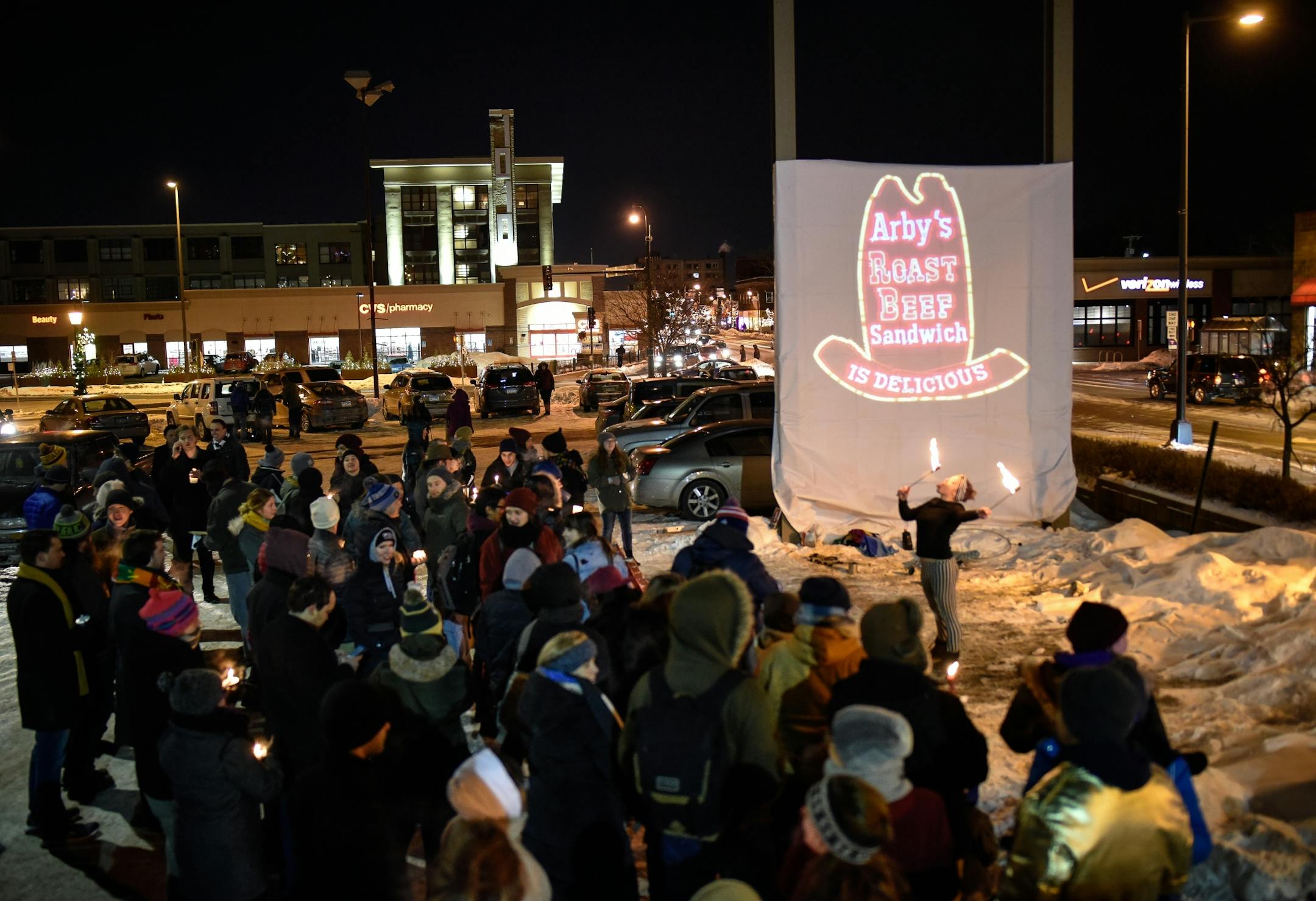 Chloe Bosak , of Andover, fire danced in front of a projected Arby's logo that was put in place of the recently-removed sign as dozens of vigil goers mourned the loss of the Uptown Arby's Friday night..