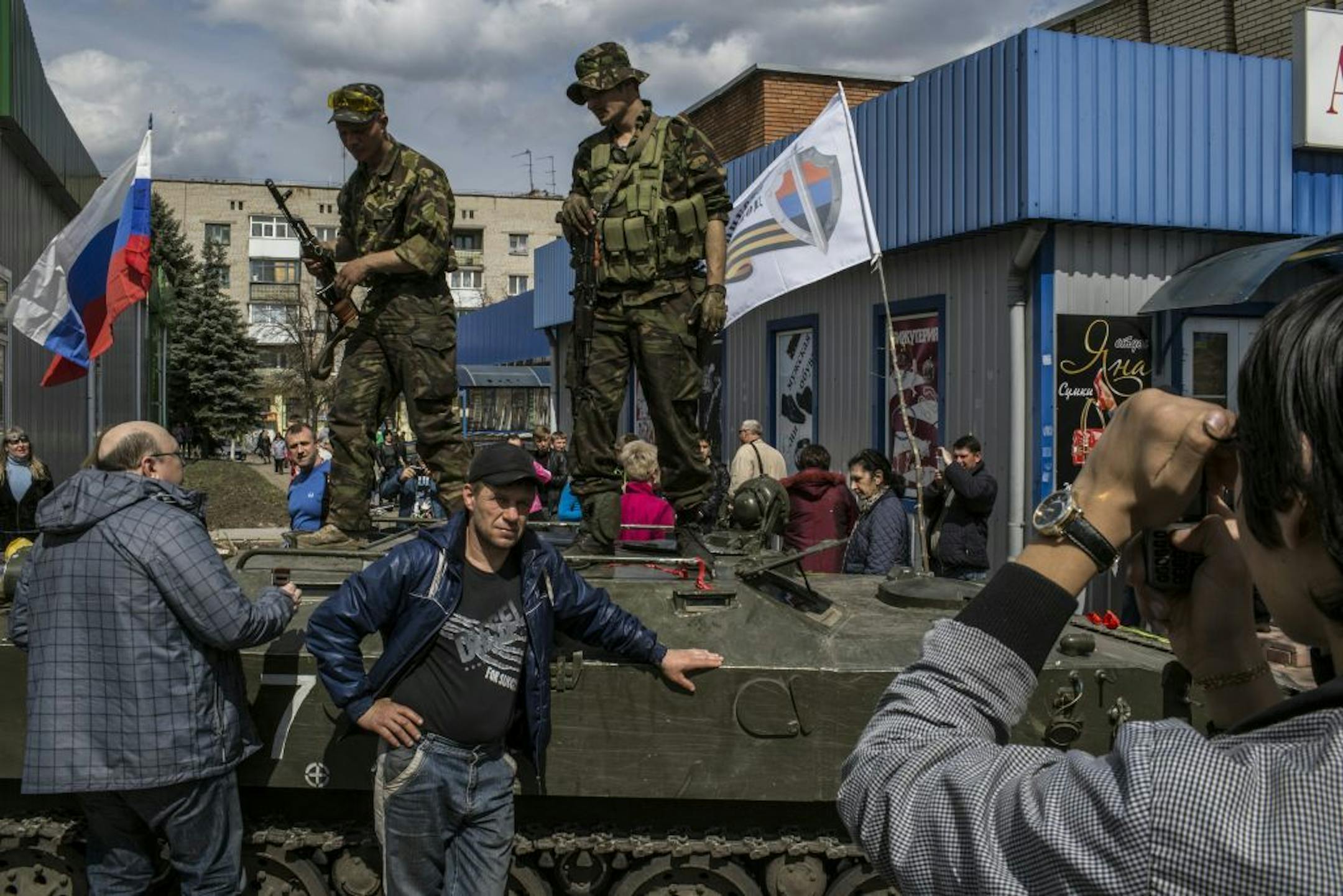 Pro-Russian militants guard an armored personnel carrier and display a Russian flag along side their militia flag near a police station in the central square of Slovyansk, Ukraine, April 16, 2014. The opening phase of what the Ukrainian government has called a military operation to confront pro-Russian militants suffered a setback Wednesday morning when six carriers were parked in the square.