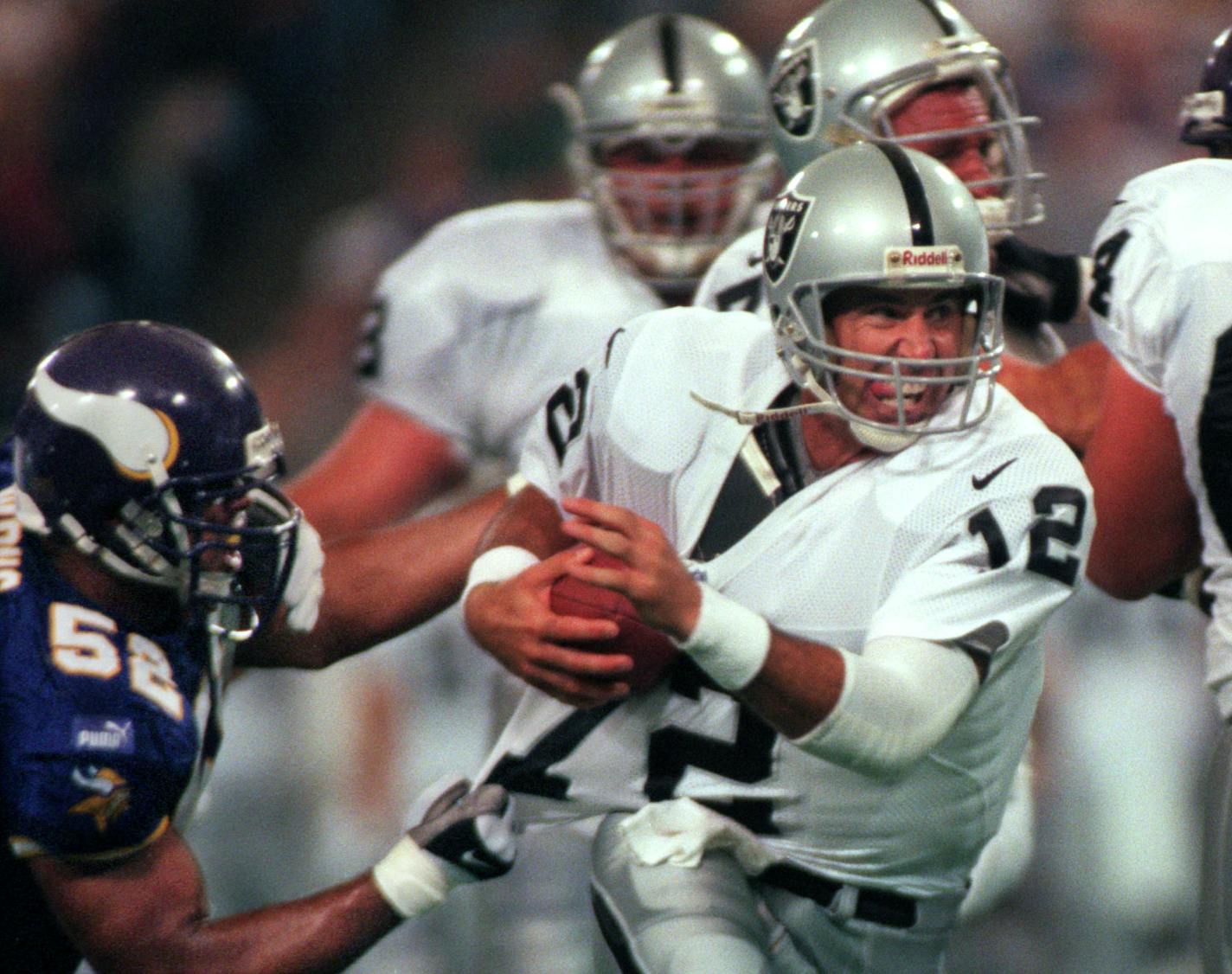 Minneapolis, MN 9/19/99 - metrodome - Vikings vs Oakland — Oakland quarterback Rich Gannon pulls away from the grasp of Minnesota linebacker Kailee Wong, left, during the first half, and manages to get the ball away in spite of the vikings attempt to sack him.