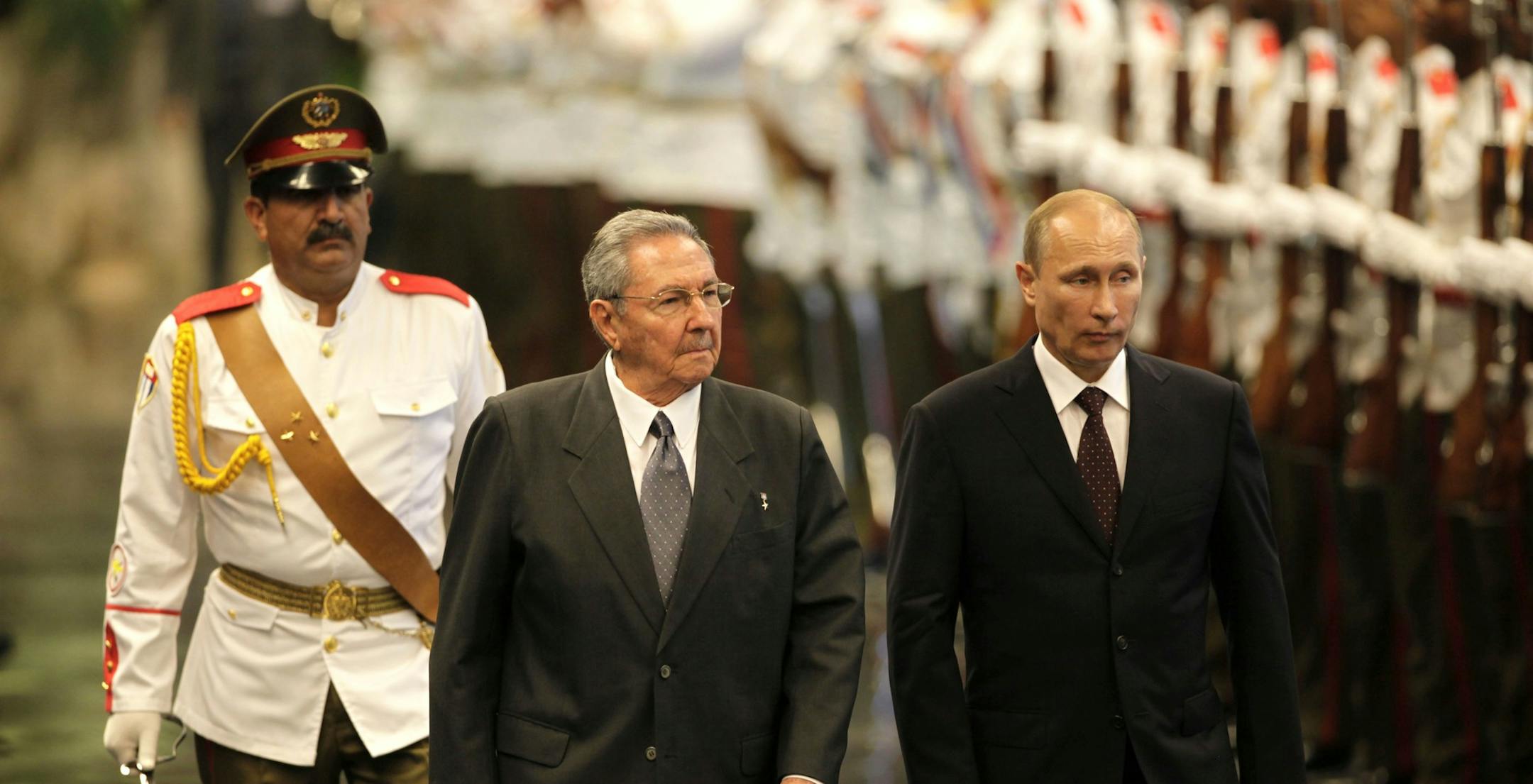 Cuba's President Raul Castro, center, and Russia's President Vladimir Putin review troops during a welcoming ceremony at Revolution Palace in Havana, Cuba, Friday, July 11, 2014. Putin began a Latin American tour aimed at boosting trade and ties in the region with a stop Friday in Cuba, a key Soviet ally during the Cold War that has backed Moscow in its dispute with the West over Ukraine. (AP Photo/Ismael Francisco, Cubadebate)