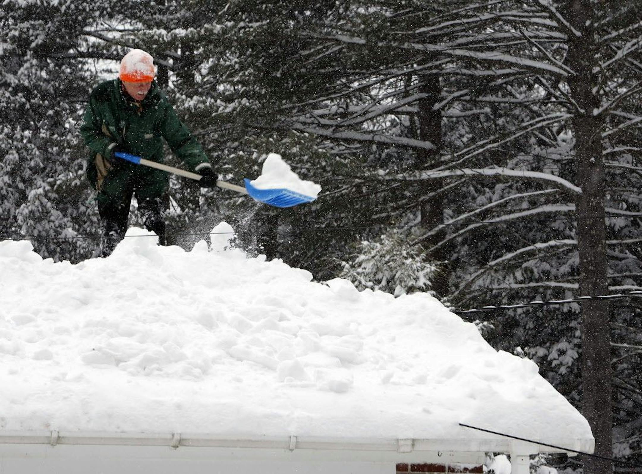 Bjorn Lange works to shovel off his roof as another snowstorm hits the area Monday, Feb. 9, 2015, in Concord, N.H.