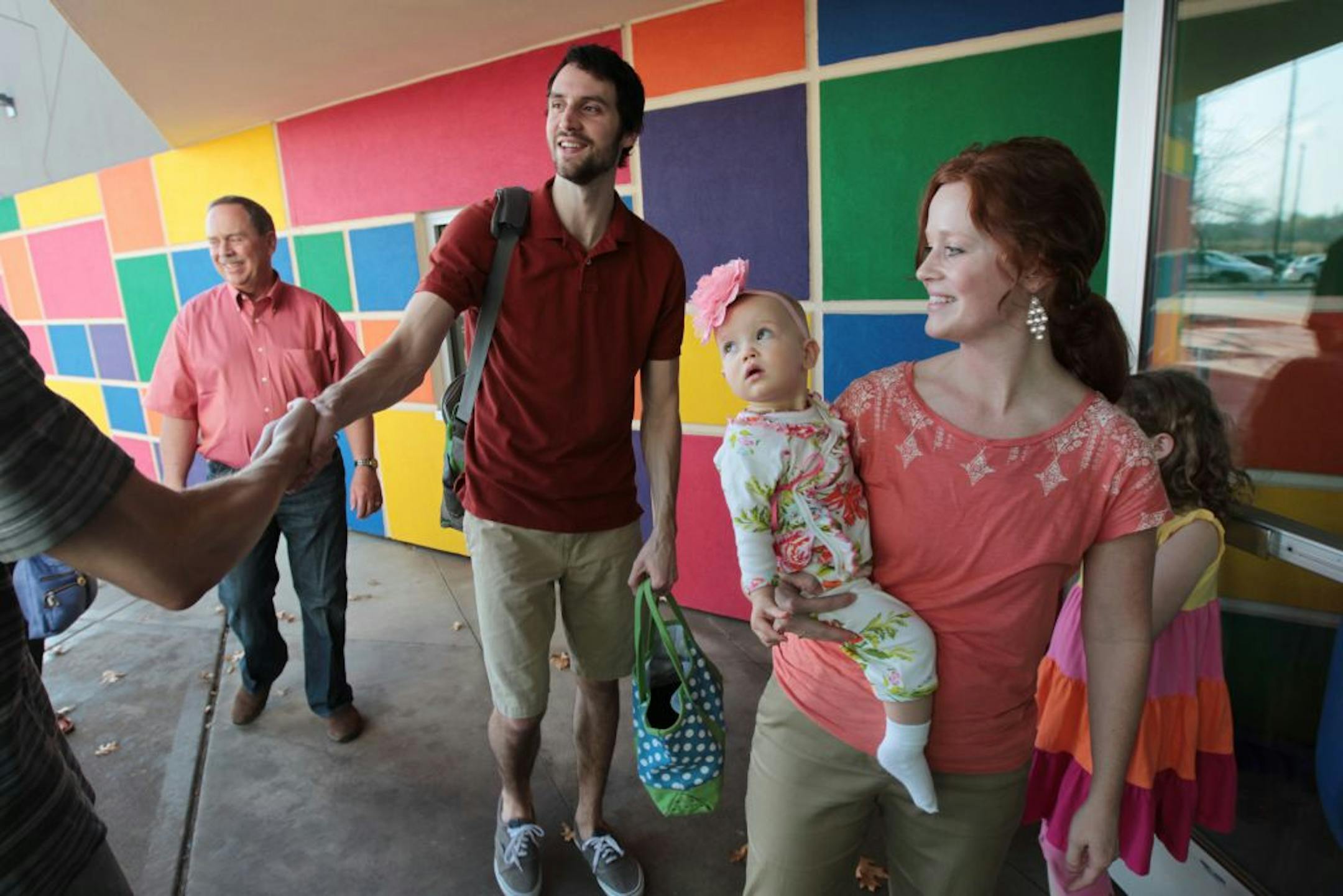 Tom Barntsen left, and his wife Sarah Barntsen with their daughter Gwendolyn 1, were welcomed as the arrived Sunday at Christ Redeemer Church in Woodbury, MN.