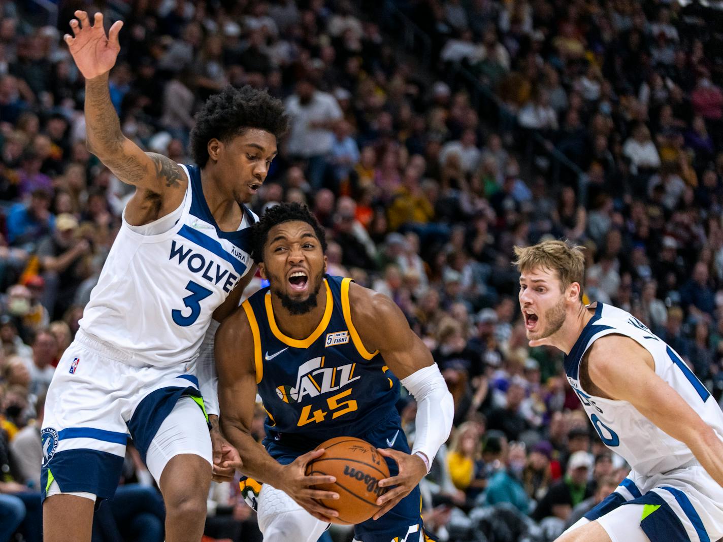 Utah Jazz guard Donovan Mitchell (45) tries to get past Minnesota Timberwolves forward Jaden McDaniels (3) as Timberwolves forward Jake Layman watches during the first half of an NBA basketball game Thursday, Dec. 23, 2021, in Salt Lake City. (AP Photo/Rick Egan)