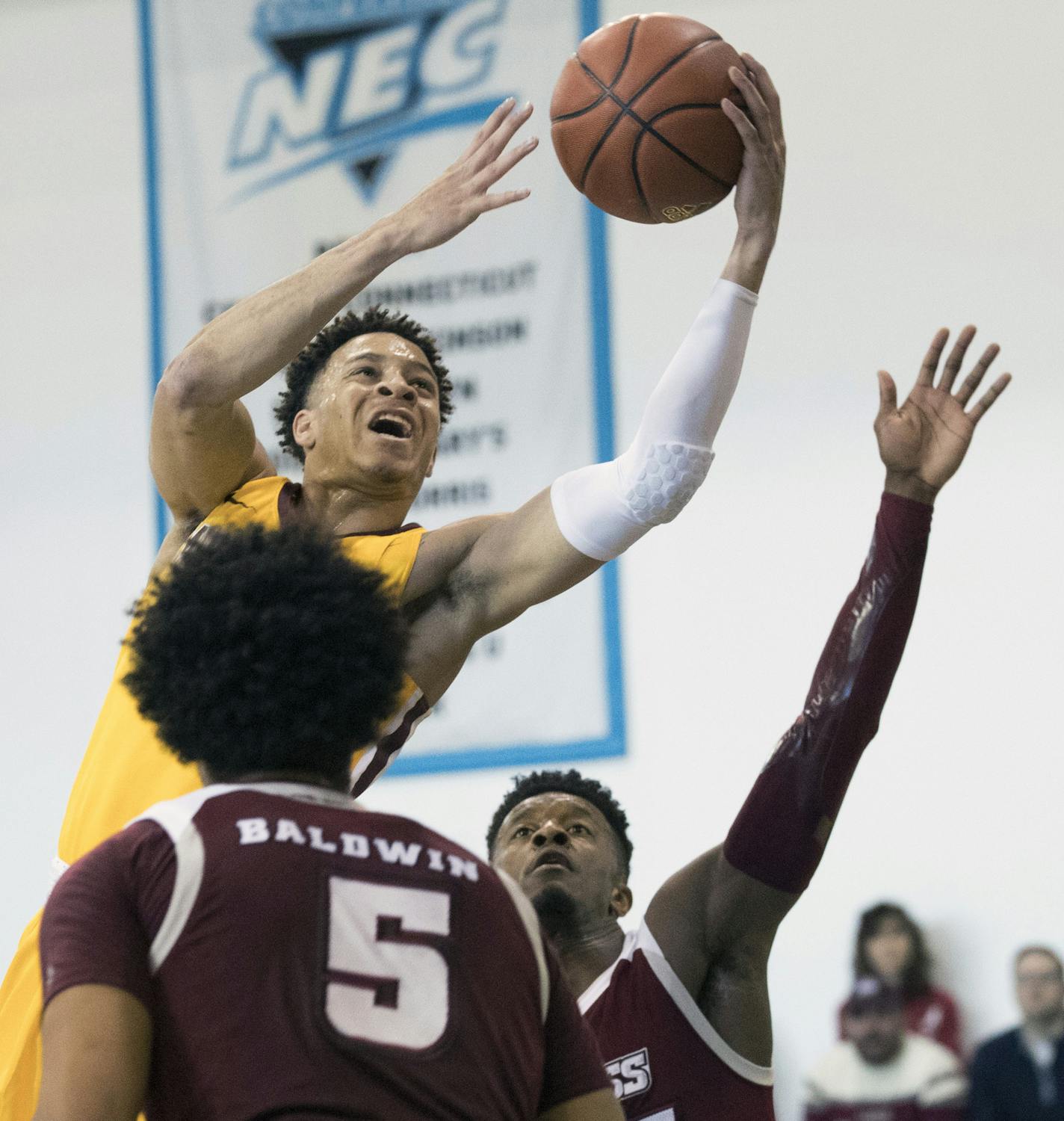 Minnesota guard Amir Coffey, center, goes to the basket against UMass forward Chris Baldwin (5) and guard C.J. Anderson during the first half of an NCAA college basketball game, Friday, Nov. 24, 2017, in New York. (AP Photo/Mary Altaffer)