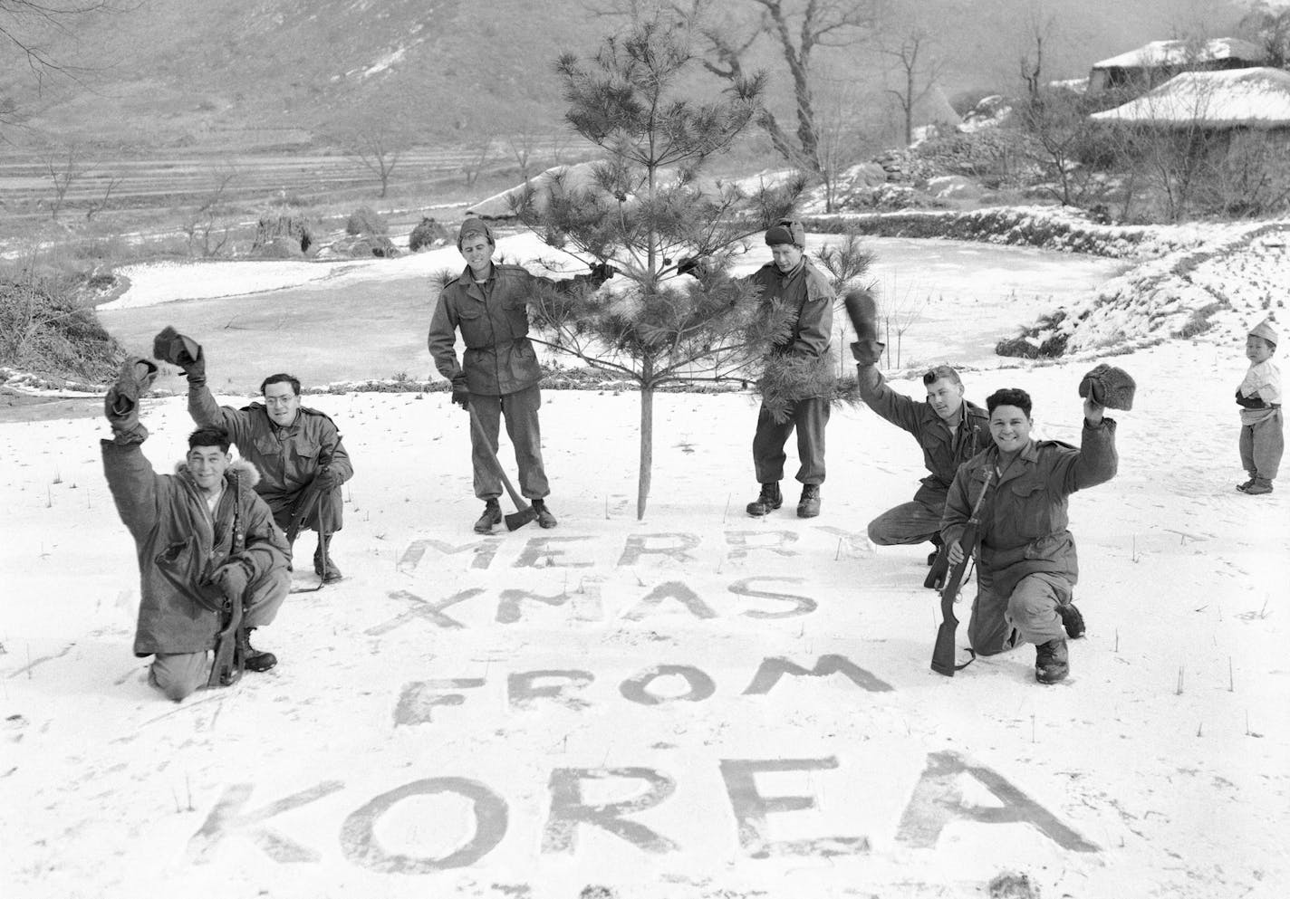 The Christmas spirit is well in evidence on the Korean front as Seventh Division GIs spell out a snowy holiday message to the folks at home on Dec. 14, 1952. A Korean youngester watches the soldiers , who are , from left to right, PFC George Torelli, New York City; PFC Mario Vairo, also of New York;PFC Elmer Devenney, Clementon , NJ; PFC Richard Coleschen, Clinton , LA; PFC Norman A. Bell , Waukegan , ILL and PFC Anthony R. Ferraro, New York City. (AP Photo/George Sweers) ORG XMIT: APHS101127