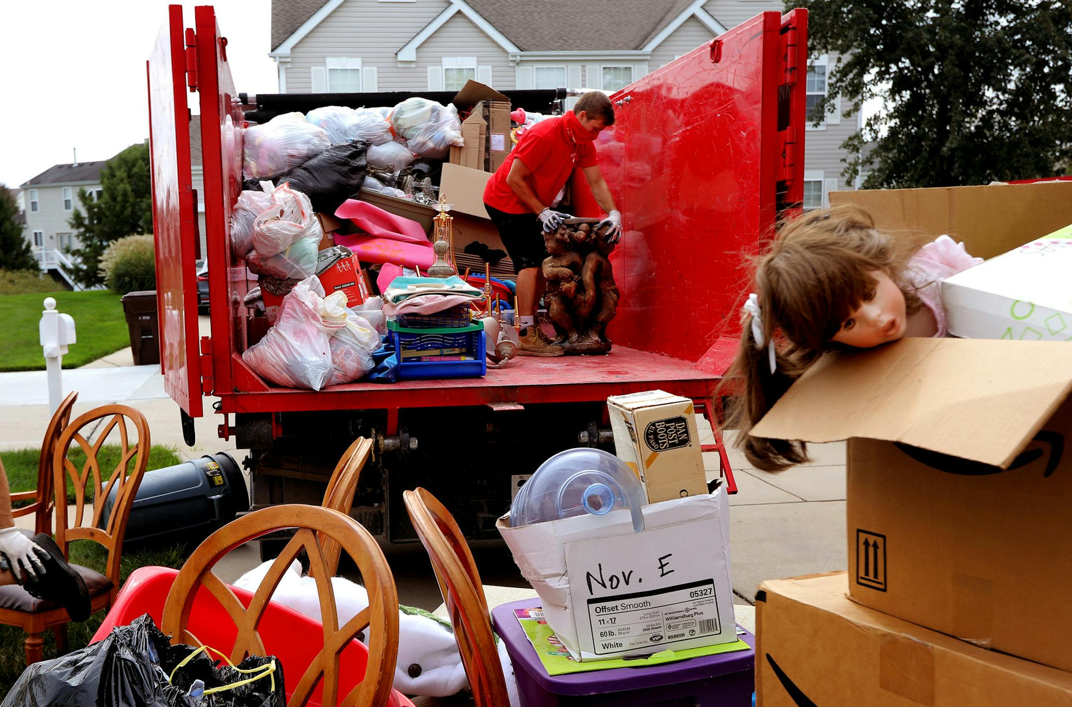 "We just never know what we might pick up," said mover Brandon Smith, right, with Junk King, who moves a stone lawn ornament so he can fit more boxes and bags full of unwanted items from a home on Tuesday, Sept. 22, 2020, in Lake St. Louis. To the left is mover Evan Pennycook. (Laurie Skrivan/St. Louis Post-Dispatch/TNS) ORG XMIT: 1788091