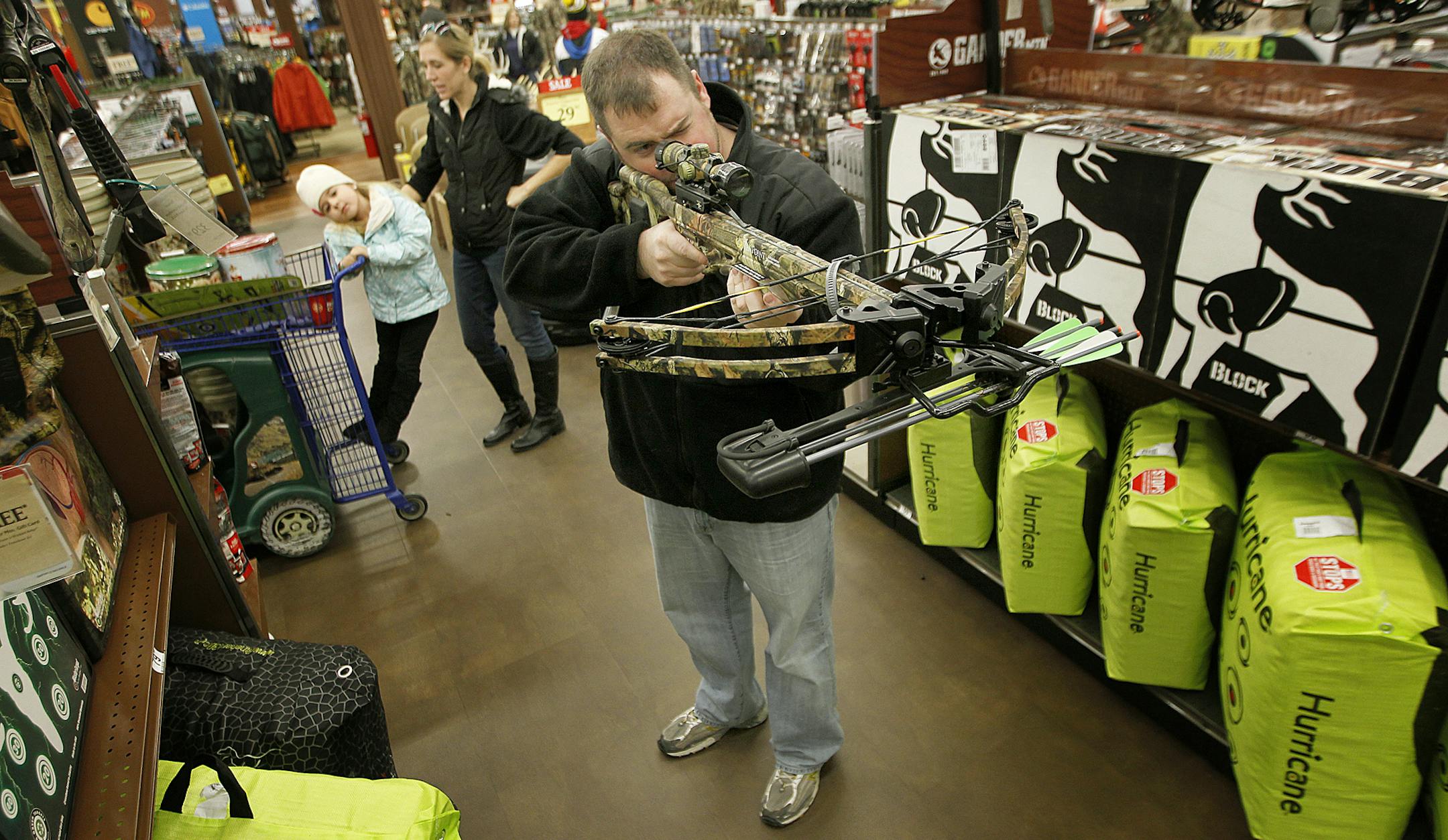 T.J. Kvilhaug, checked out a bow, along with his wife Bria, center, and two daughters Madison, 5, left, and Avery, 3, during "Black Friday" shopping at Gander Mountain, in Woodbury, MN. (ELIZABETH FLORES/STAR TRIBUNE) ELIZABETH FLORES • eflores@startribune.com
