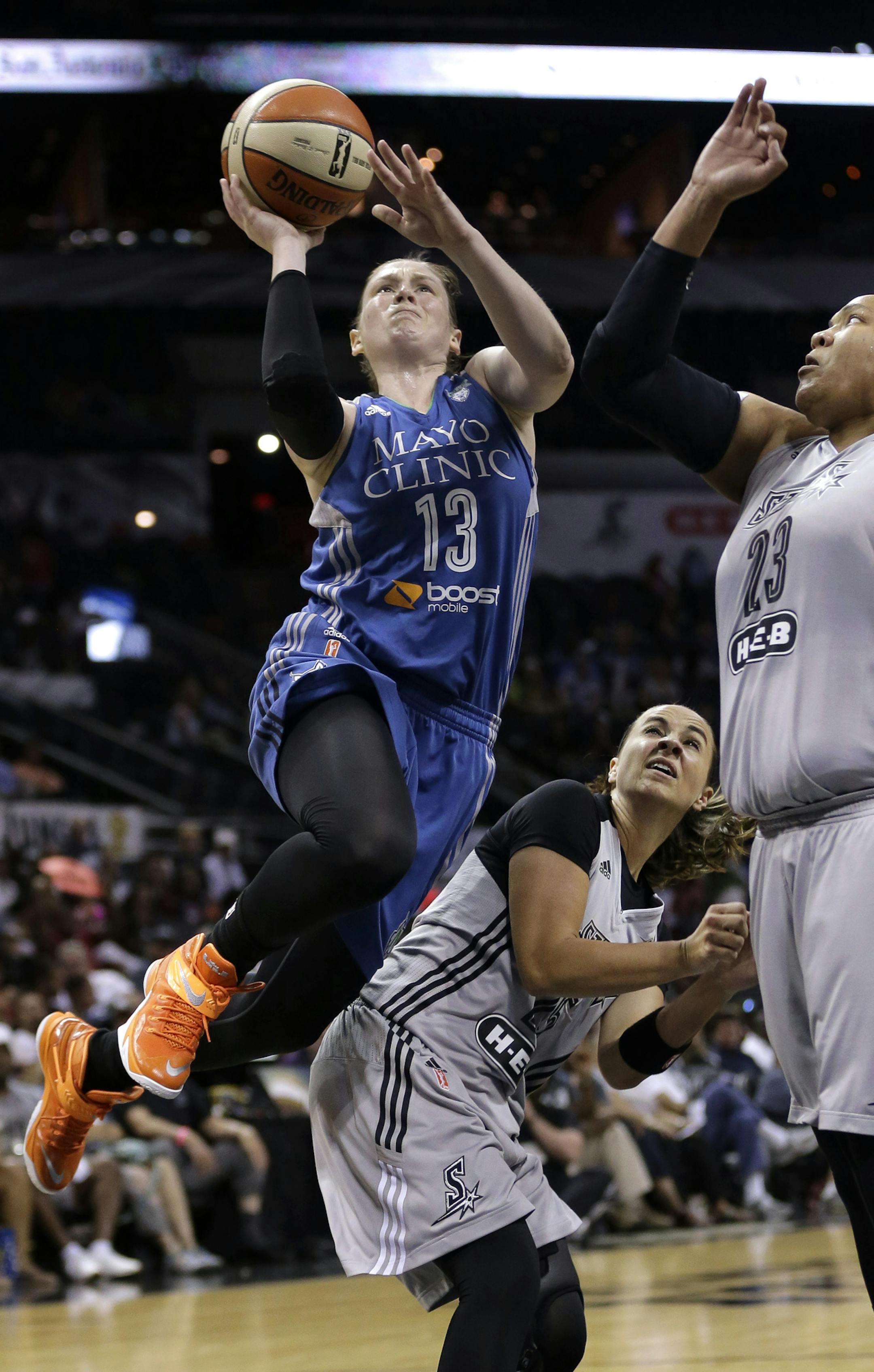 Minnesota Lynx's Lindsay Whalen (13) shoots over San Antonio Stars' Becky Hammon, center, and Danielle Adams (23) during the first half in Game 2 of the WNBA basketball Western Conference semifinal, Saturday, Aug. 23, 2014, in San Antonio. (AP Photo/Eric Gay)